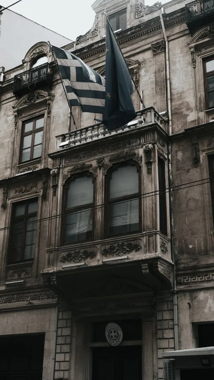 Façade néoclassique d'un consulat grec, drapeaux grec et européen au balcon