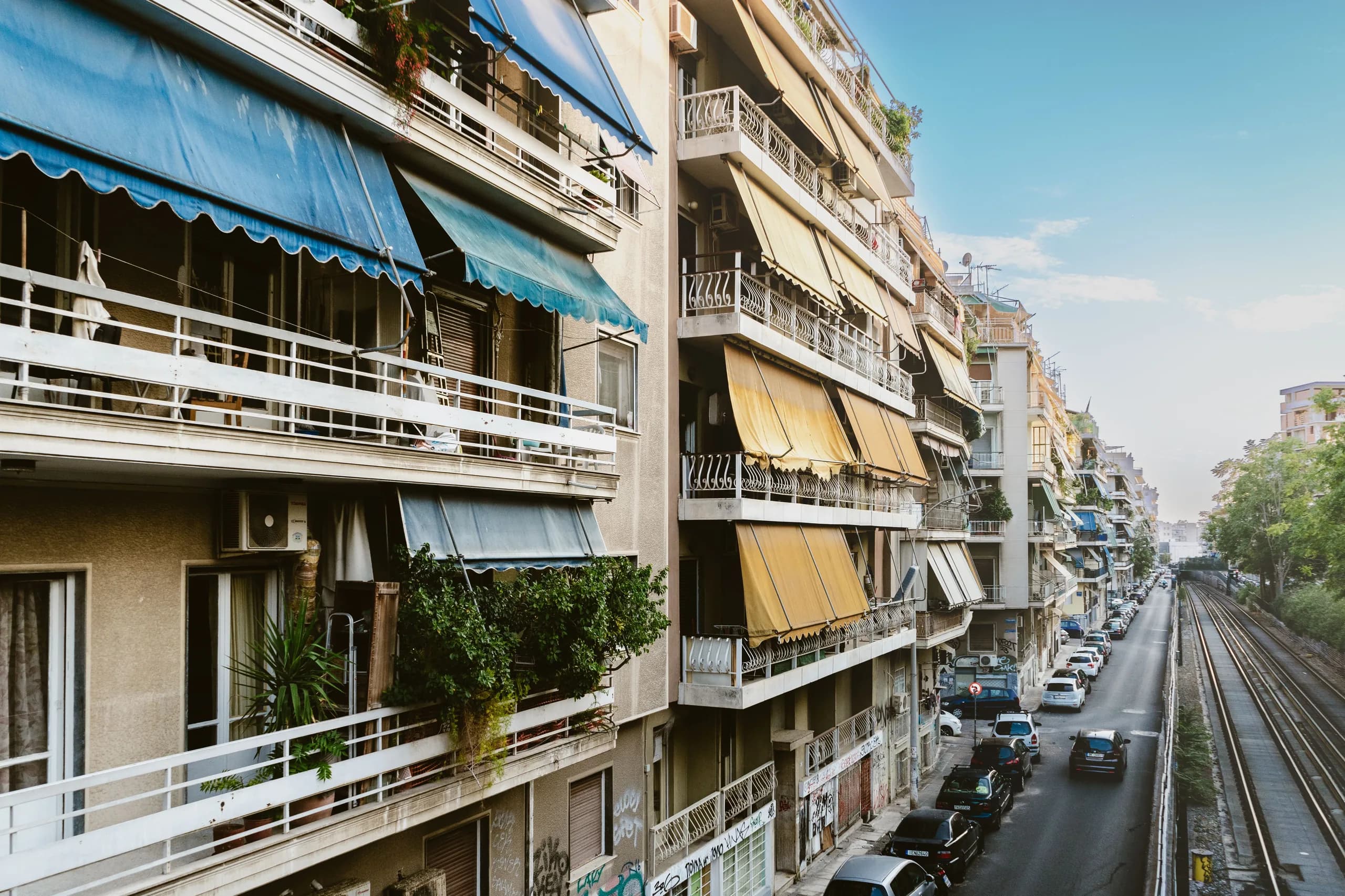 Rue résidentielle d'Athènes bordée d'immeubles à balcons et stores