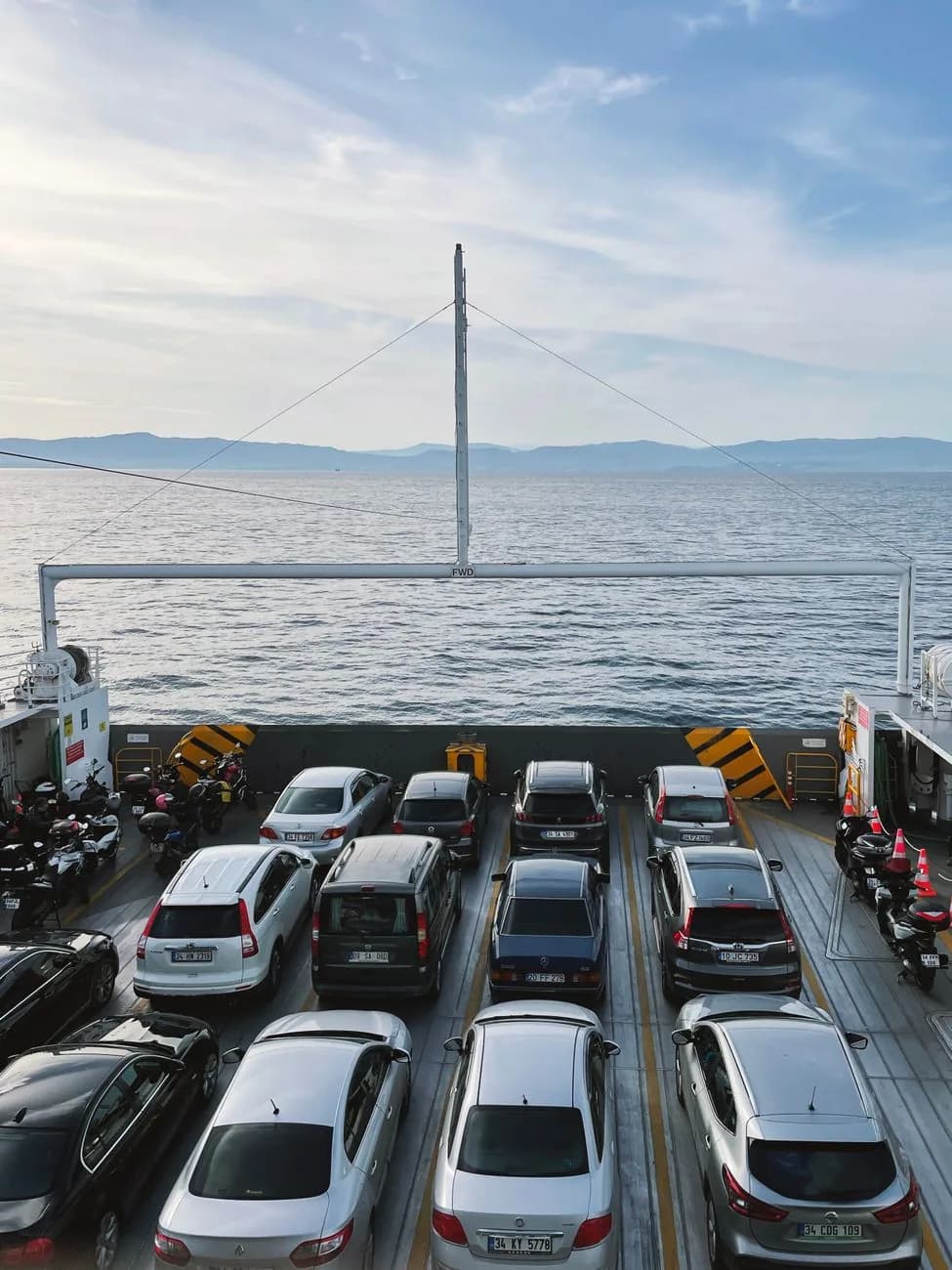 Le pont-garage d'un ferry chargé de voitures et de scooters, la mer visible au-delà du bastingage