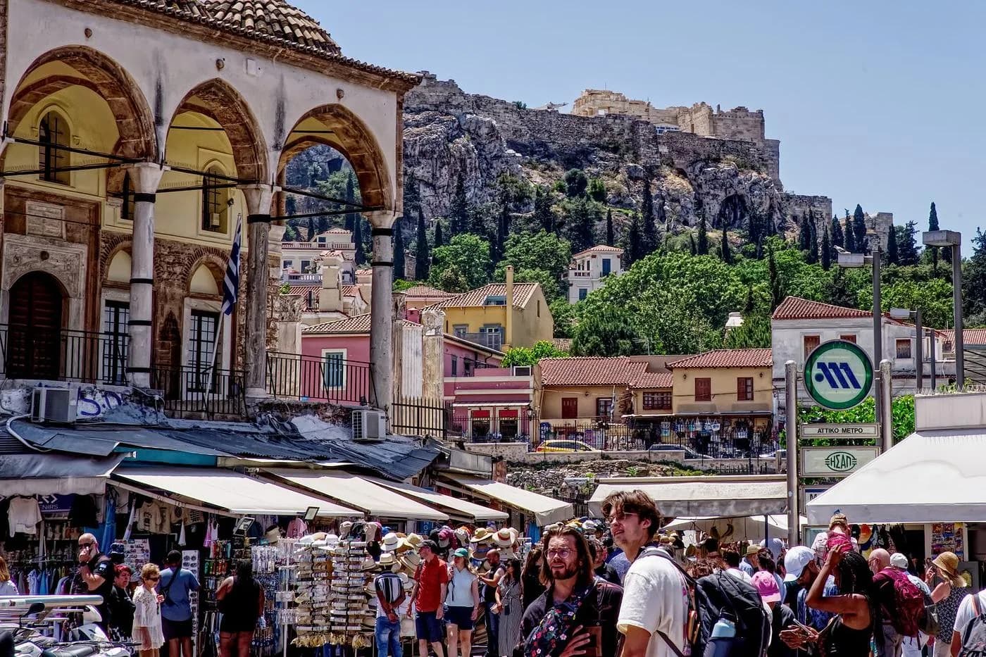 Boutiques à auvents et passants près de la place Monastiraki à Athènes, avec l'Acropole en arrière-plan