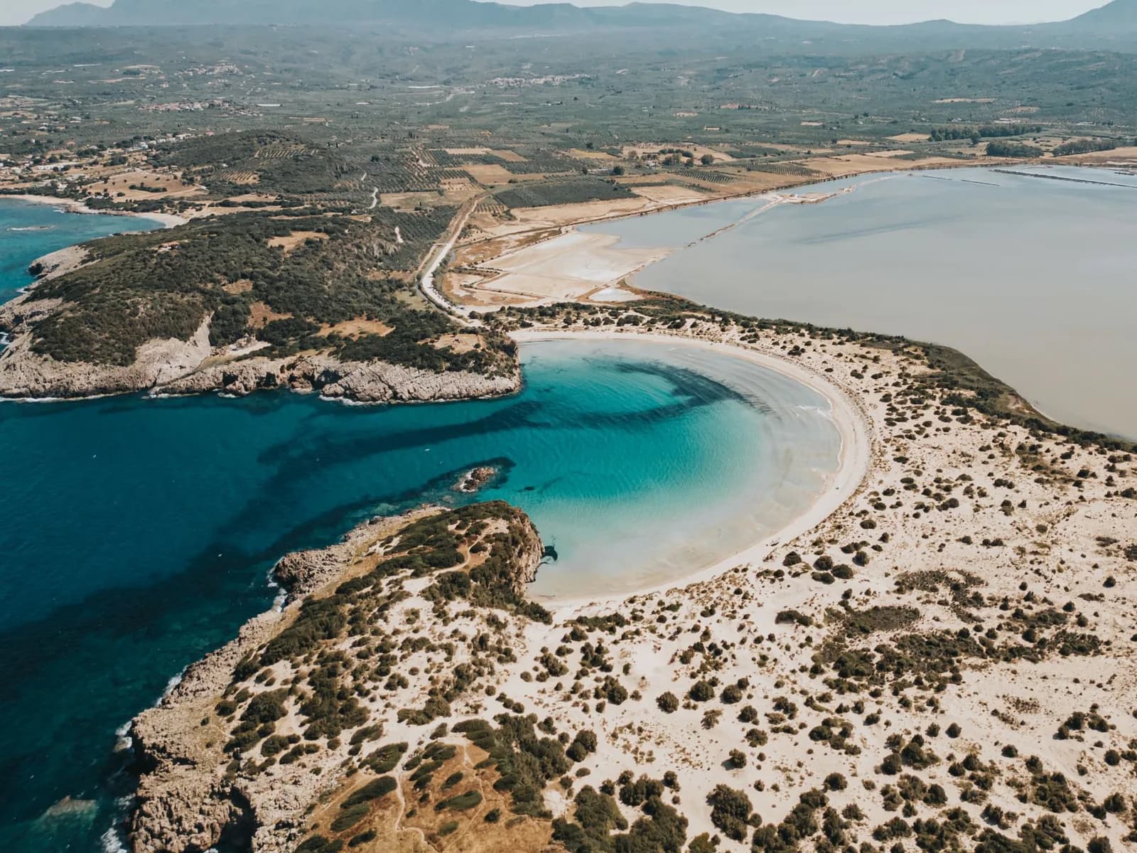 Vue aérienne de la plage de Voïdokilia en Messénie, son arc de sable blanc en forme d'oméga entre la mer Ionienne et la lagune de Gialova, dans le sud-ouest du Péloponnèse