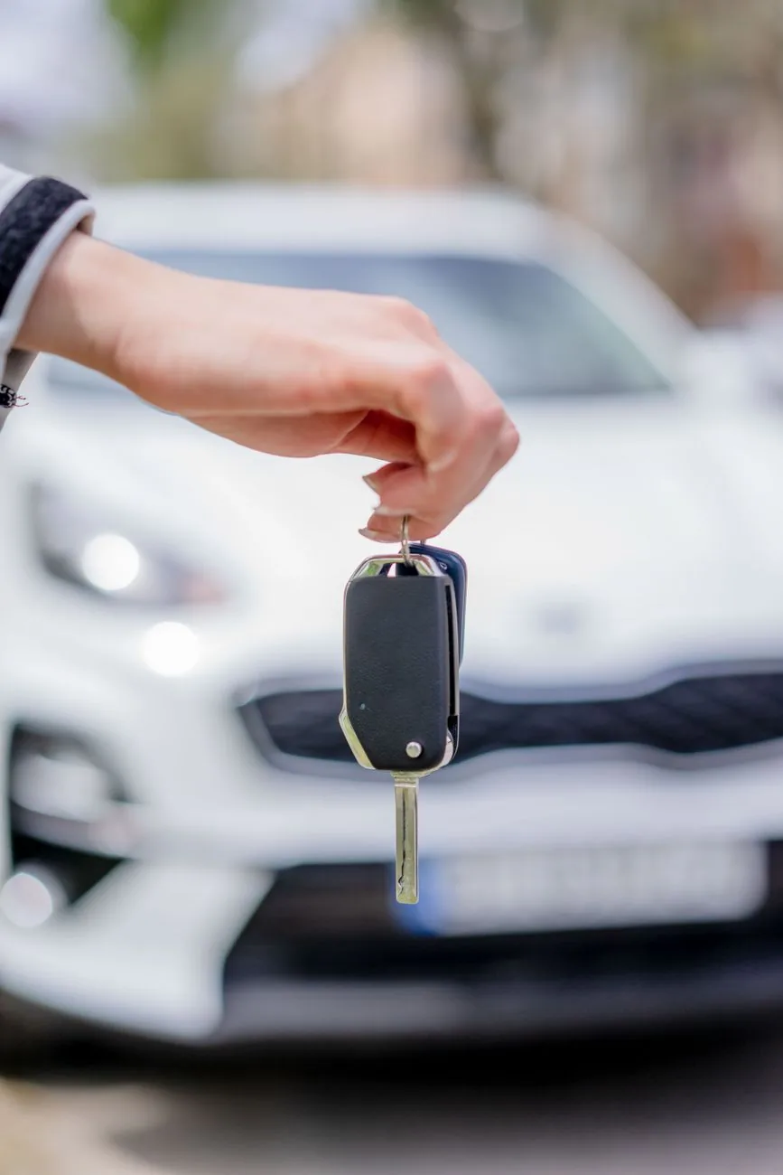 Remise des clés d'une voiture de location blanche devant l'agence