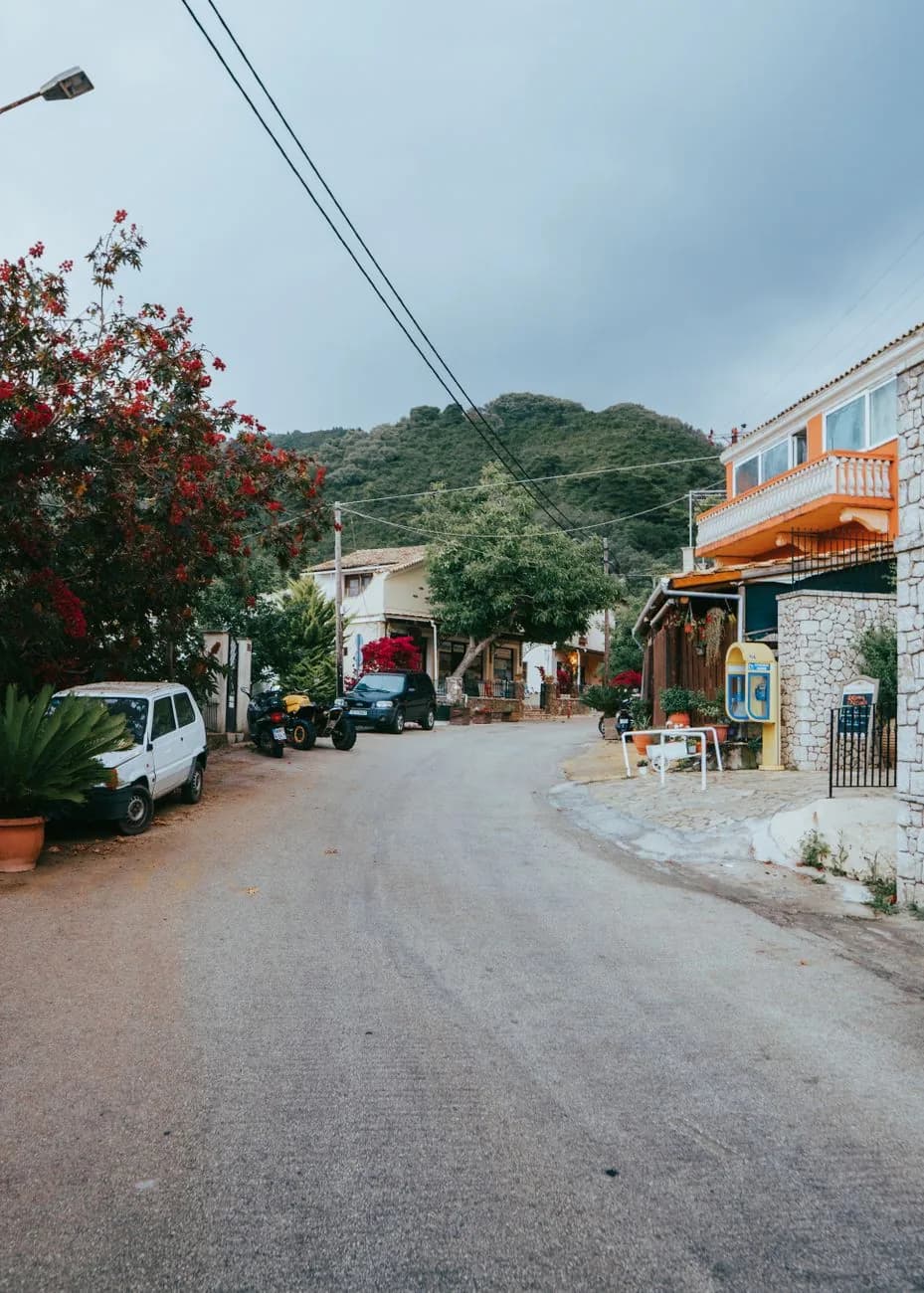 Petites voitures et scooters garés le long de la rue étroite d'un village grec