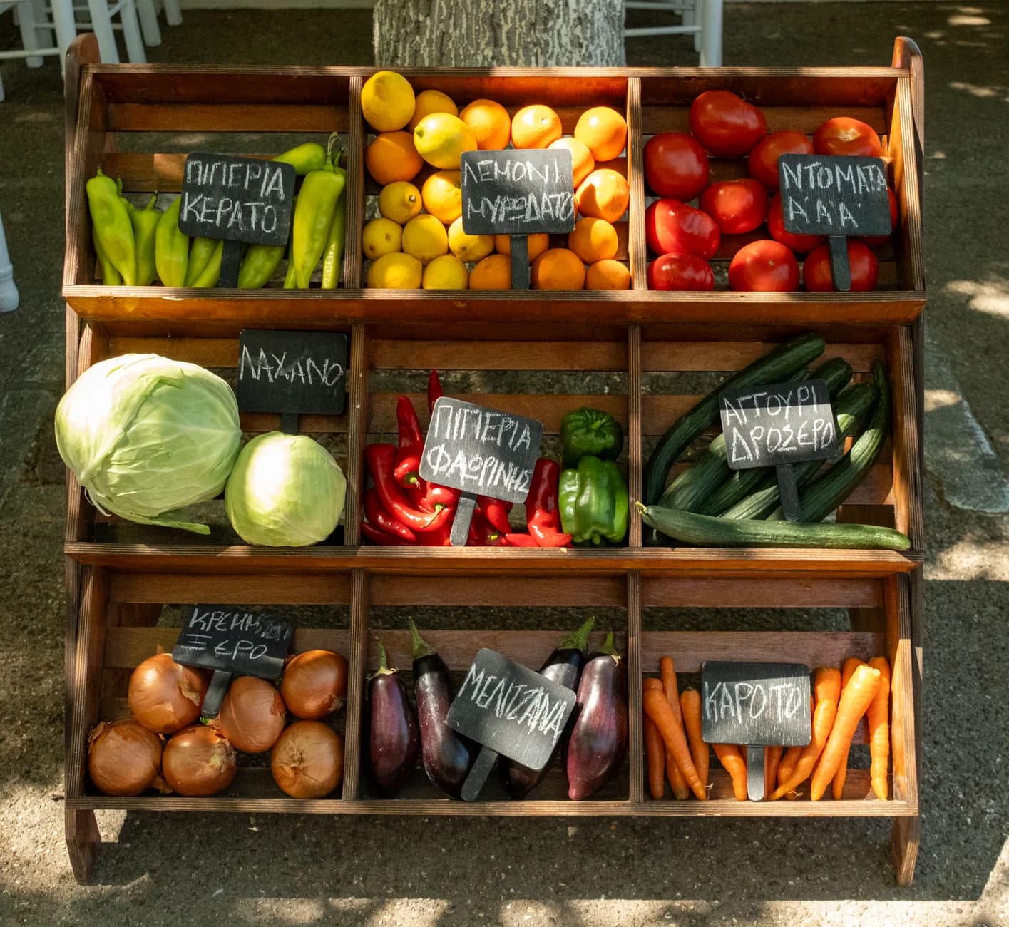 Étal de fruits et légumes d'un marché grec, aux ardoises de prix écrites en grec, où tout se règle en espèces