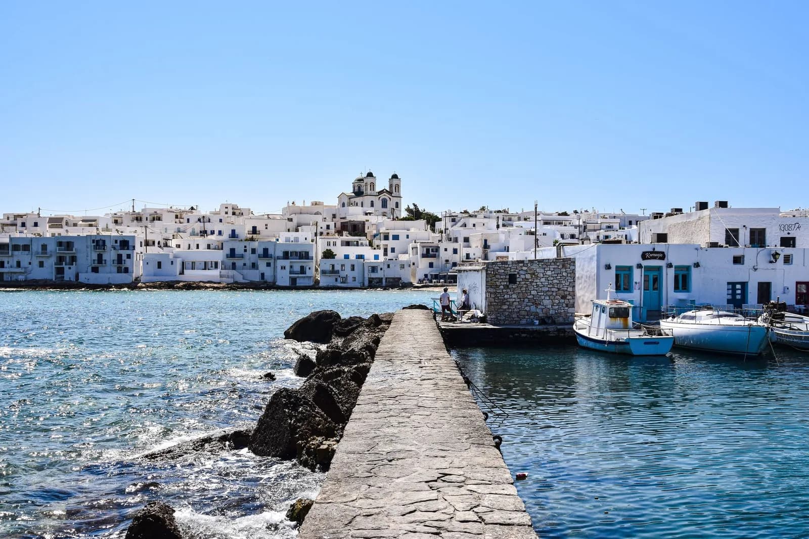 La jetée de pierre du petit port fortifié de Naoussa, avec la Chora blanche en arrière-plan, à Paros