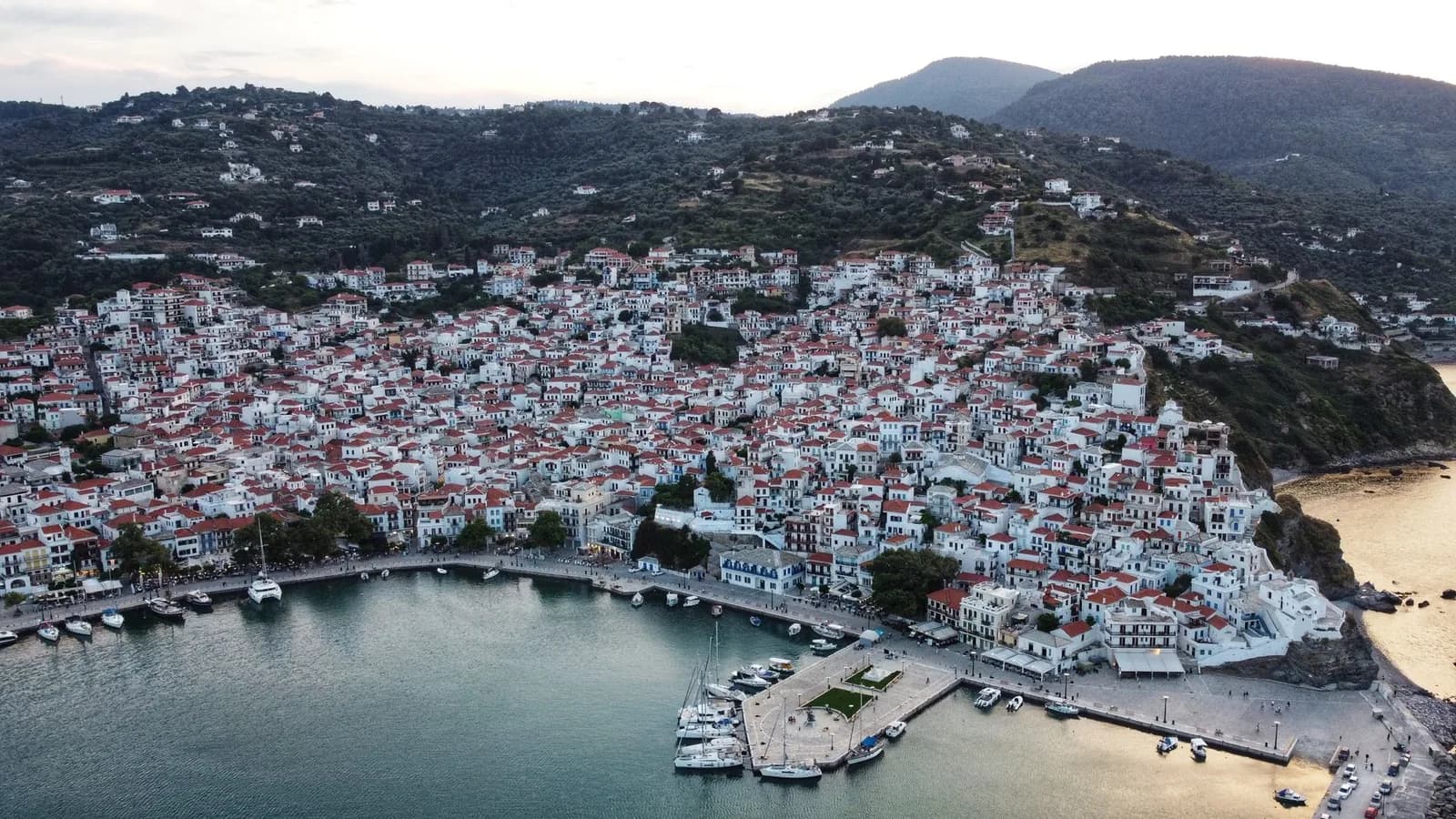 Vue aérienne de Skopelos Ville étagée en amphithéâtre au dessus de son port, avec les collines boisées de l'île derrière