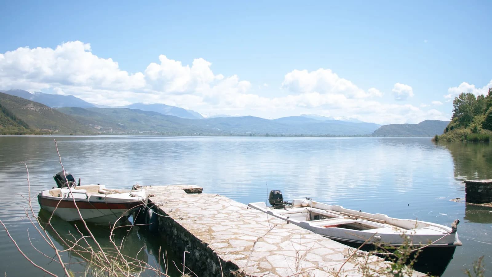 Ponton et barques sur le lac Pamvotis à Ioannina, avec les montagnes de l'Épire en toile de fond