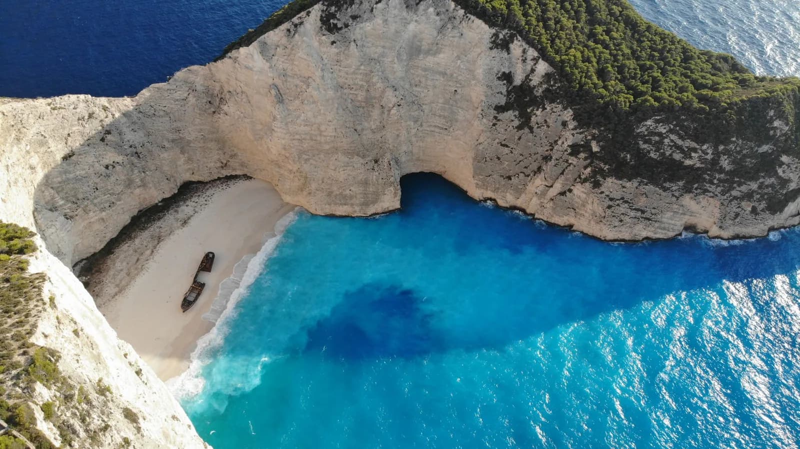 Vue aérienne de la plage du Navagio à Zante, son épave et son eau turquoise cernée de falaises blanches