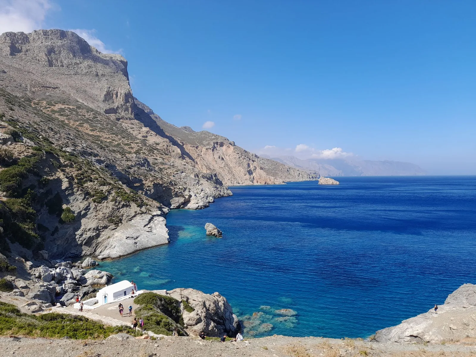 La baie d'Agia Anna à Amorgos vue d'en haut, avec sa chapelle blanche sur un promontoire rocheux et une mer bleu profond au pied des falaises