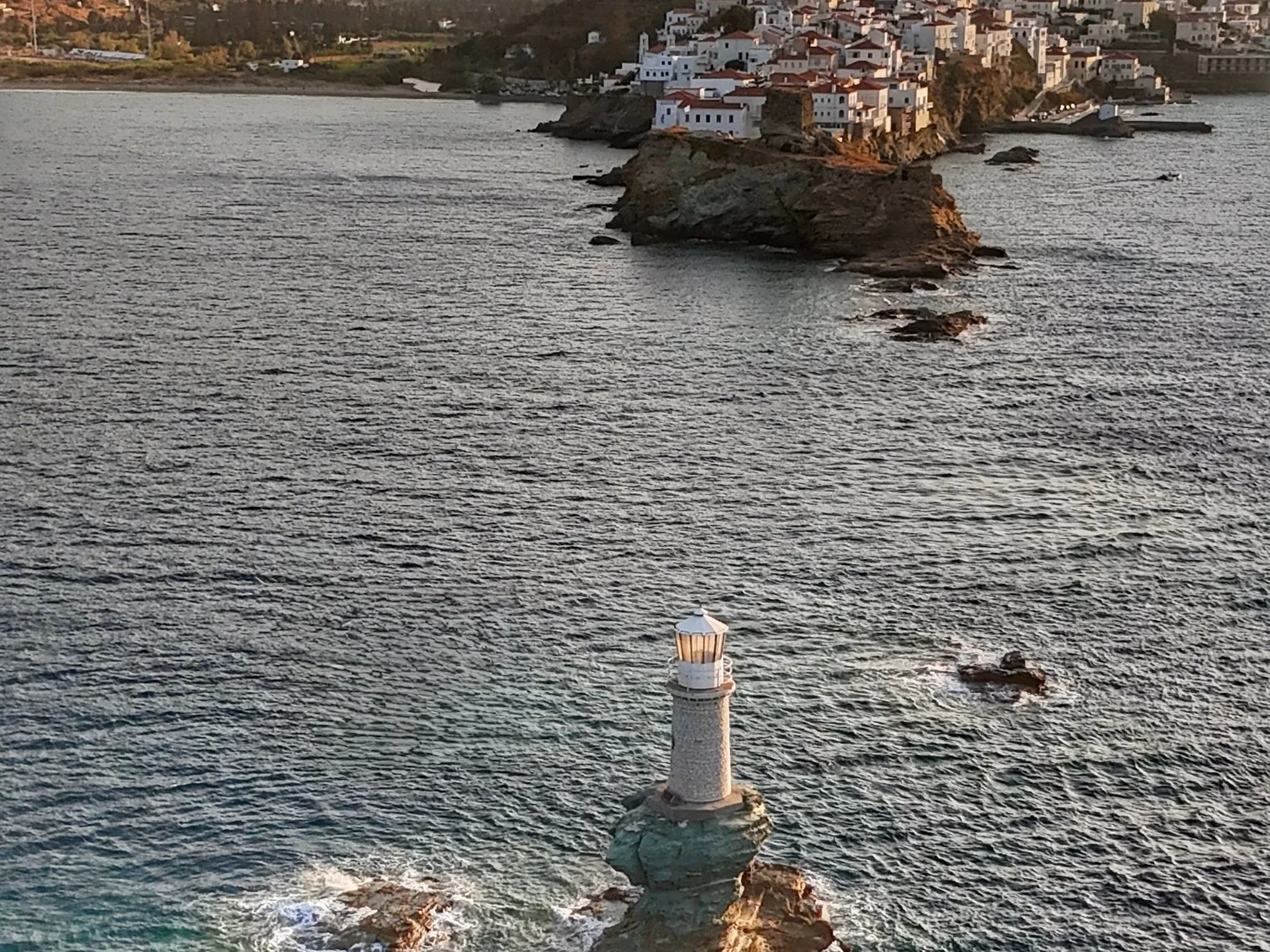 Le phare de Tourlitis dressé sur son rocher face à la Chora d'Andros, avec les ruines du château vénitien
