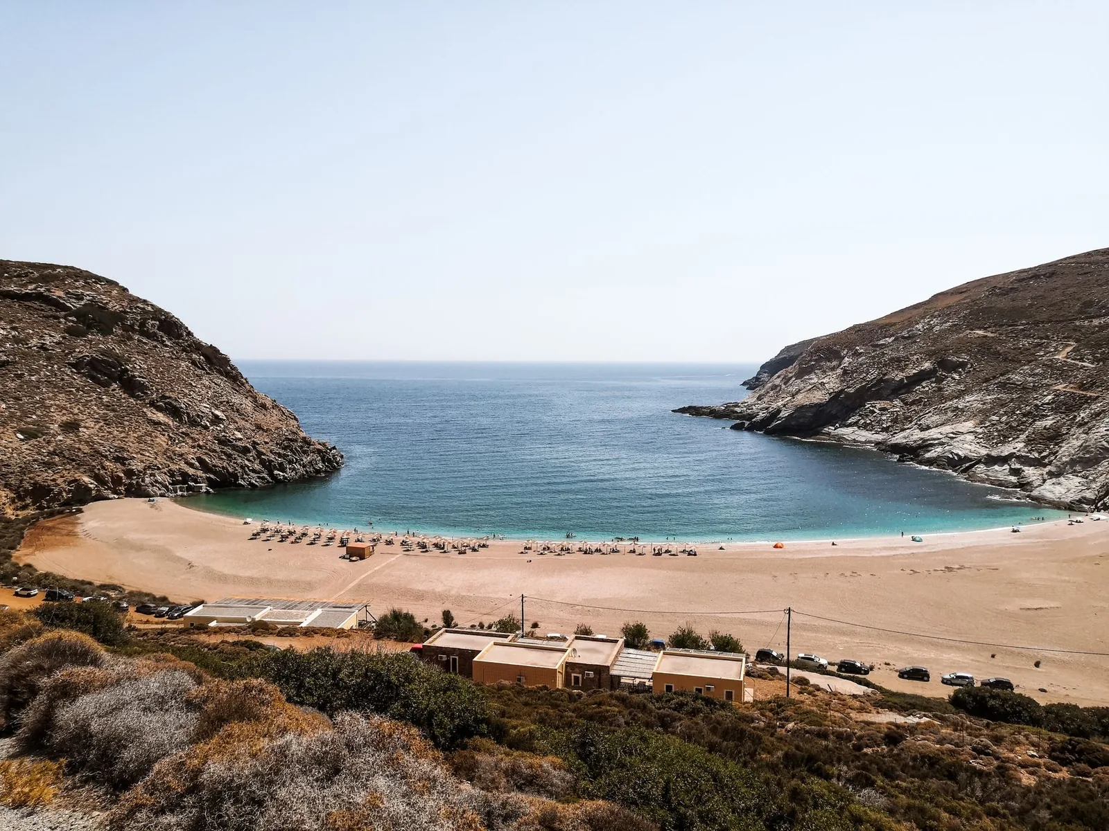 Plage de sable en fer à cheval encadrée par deux promontoires rocheux, sur la côte d'Andros