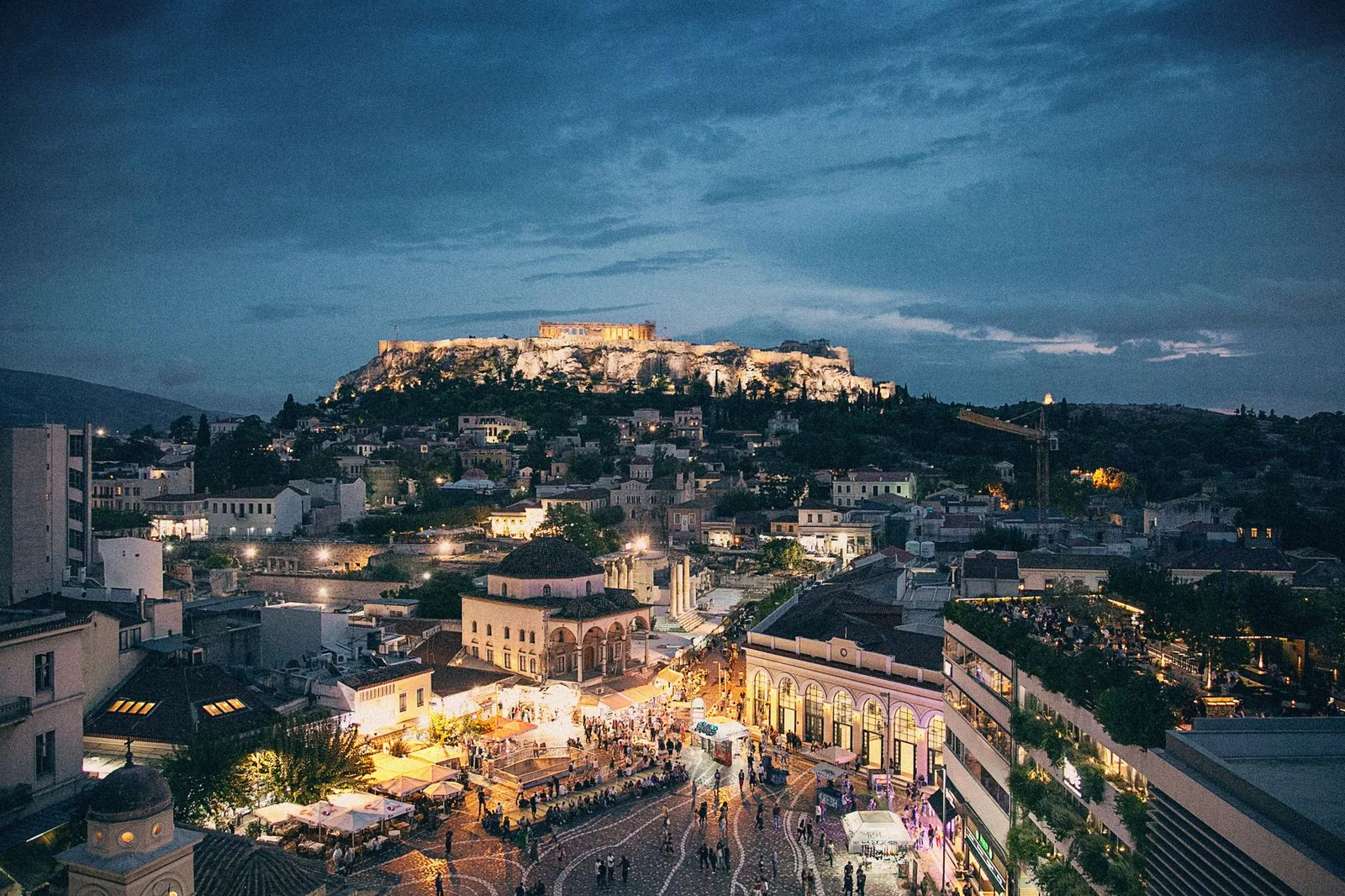 La place Monastiraki et l'Acropole illuminée à la tombée de la nuit, vues depuis un toit-terrasse d'Athènes