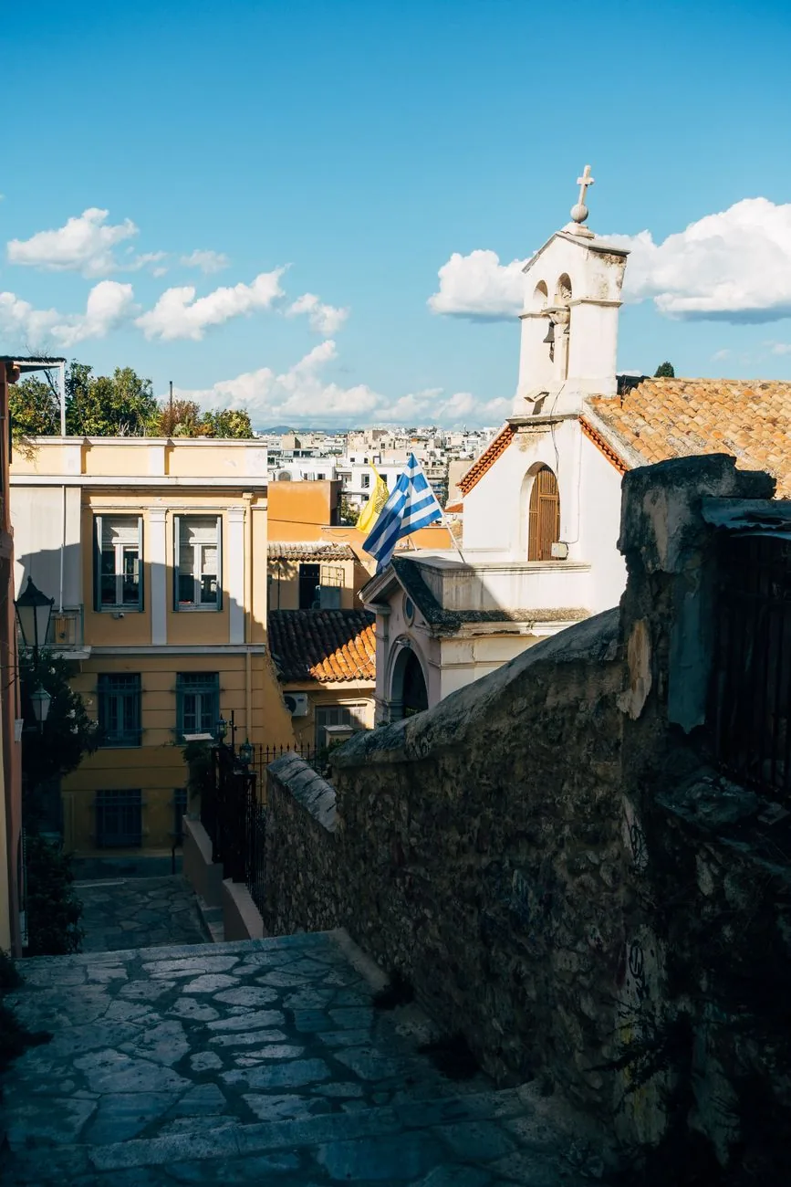 Escalier de pierre et petite église blanche à clocher-mur sur les pentes de l'Acropole, dans le haut de Plaka à Athènes