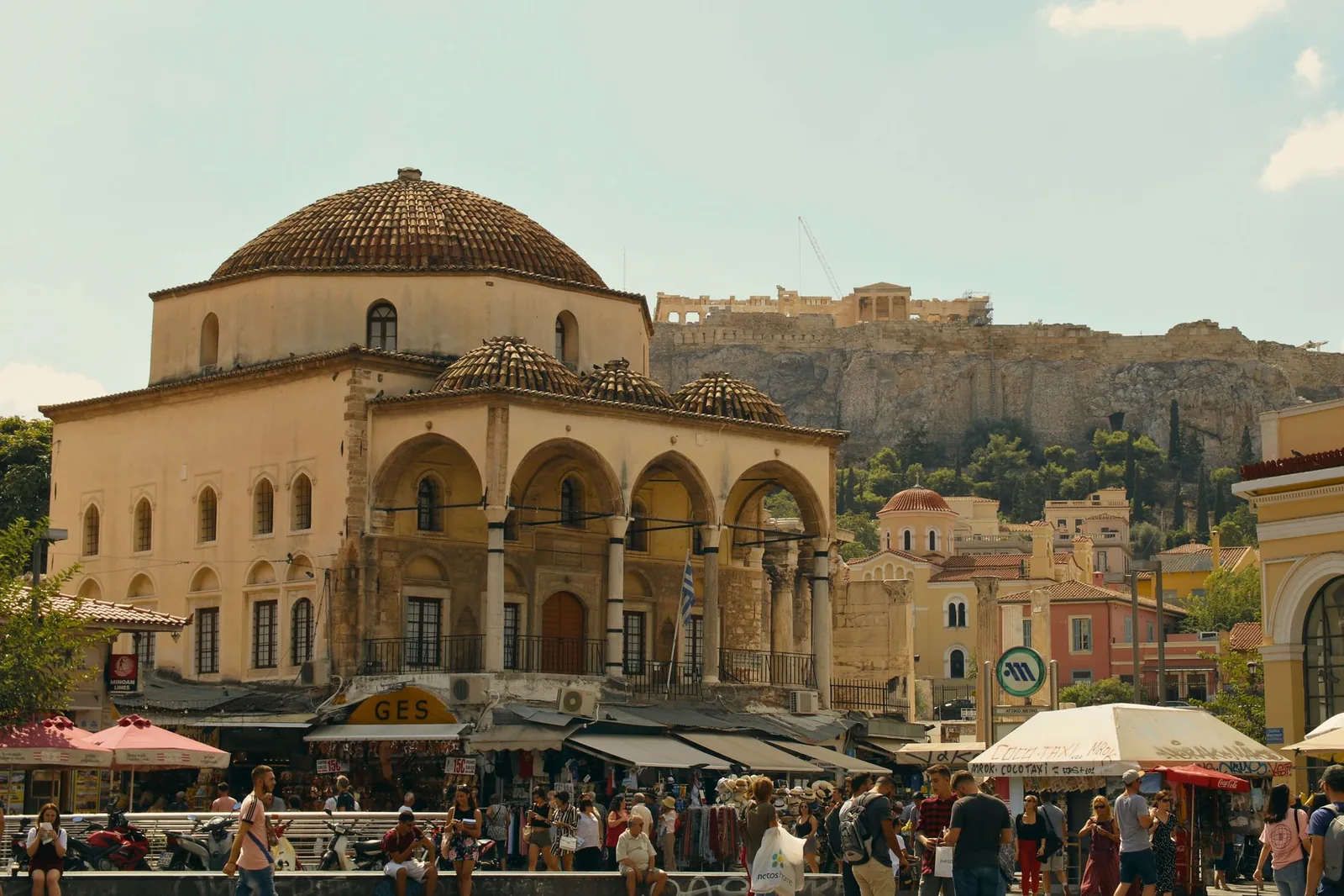 La place Monastiraki à Athènes avec la mosquée Tzistarakis, les étals et le rocher de l'Acropole en arrière-plan