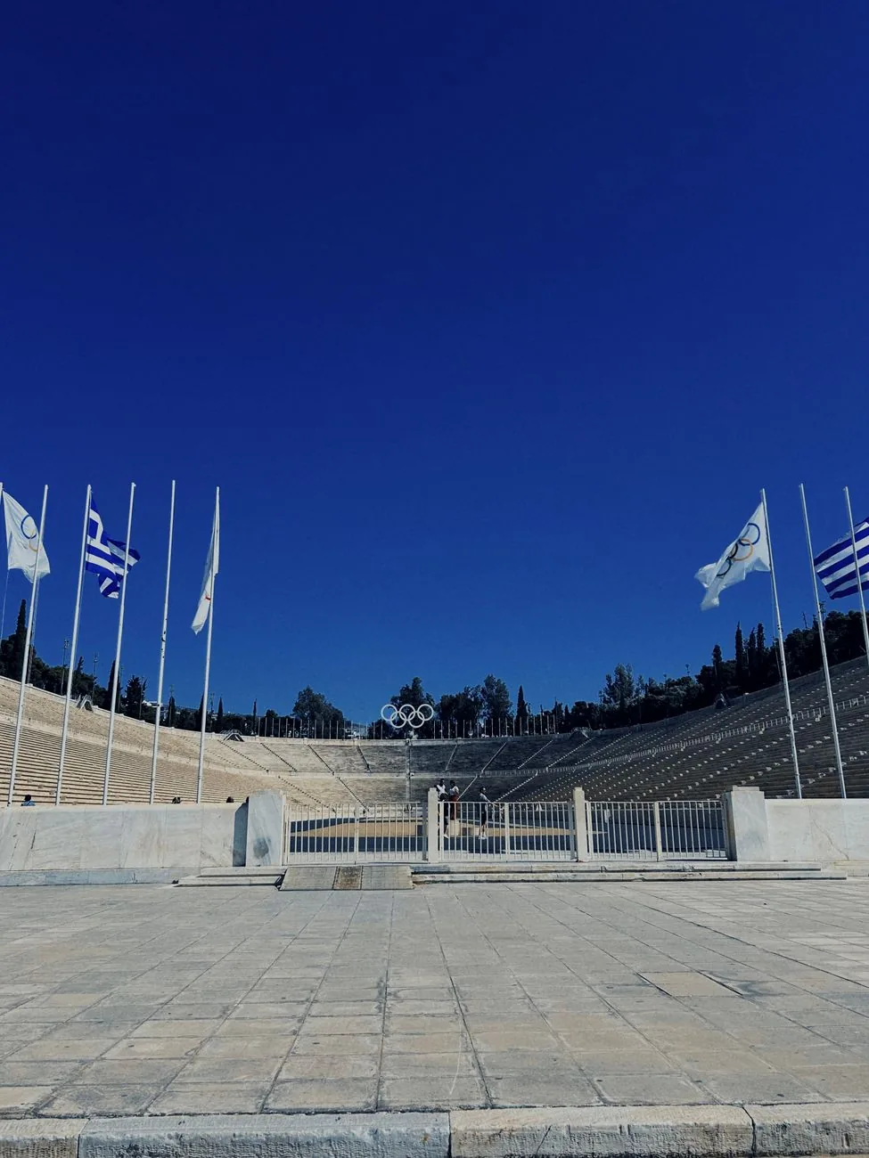 Les gradins de marbre blanc du stade panathénaïque d'Athènes et les drapeaux olympiques devant l'entrée