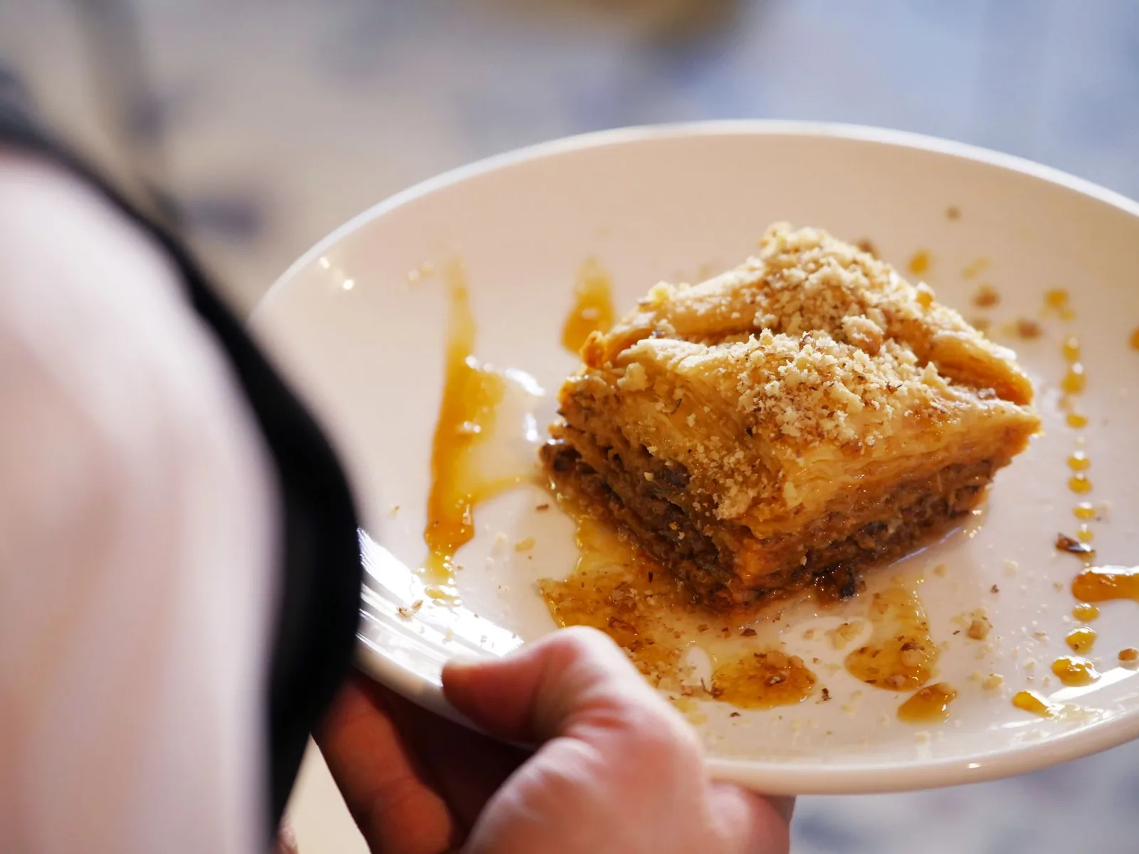 Part de baklava grec aux noix, feuilles de filo croustillantes et sirop de miel, servie dans une assiette blanche