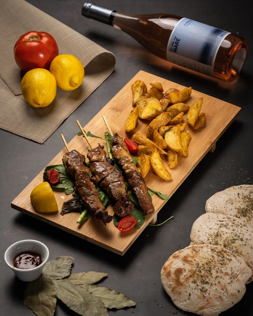 Brochettes de souvlaki grecques grillées servies sur une planche avec des pommes de terre rôties, du pain pita et du citron