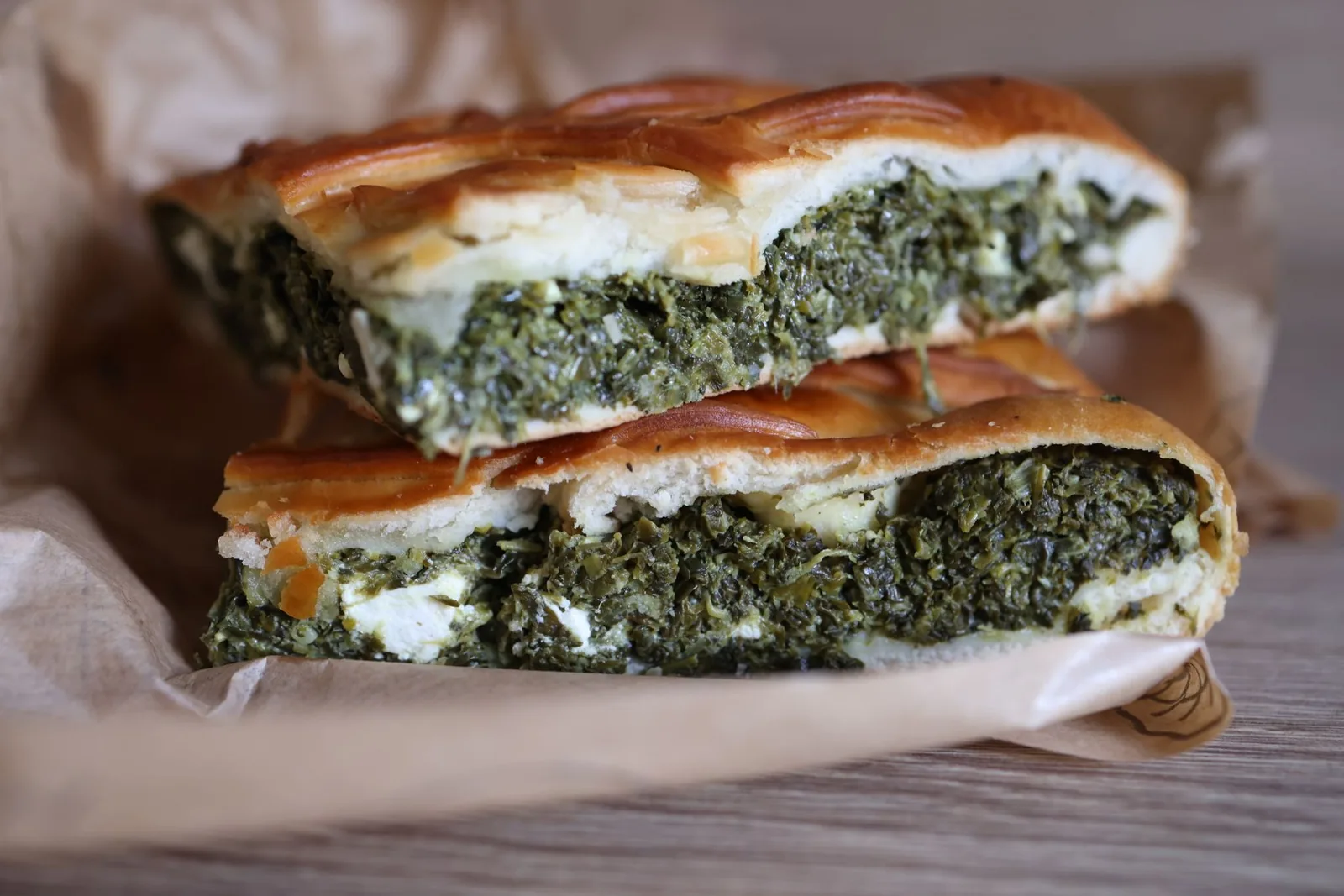 Parts de spanakopita grecque, tourte feuilletée aux épinards et à la feta, posées sur du papier kraft