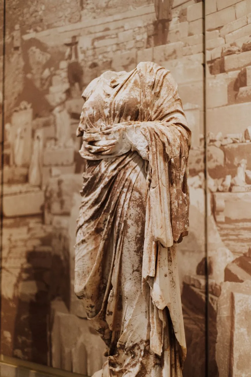 Statue de marbre drapée sans tête exposée dans une salle du musée archéologique de Delphes