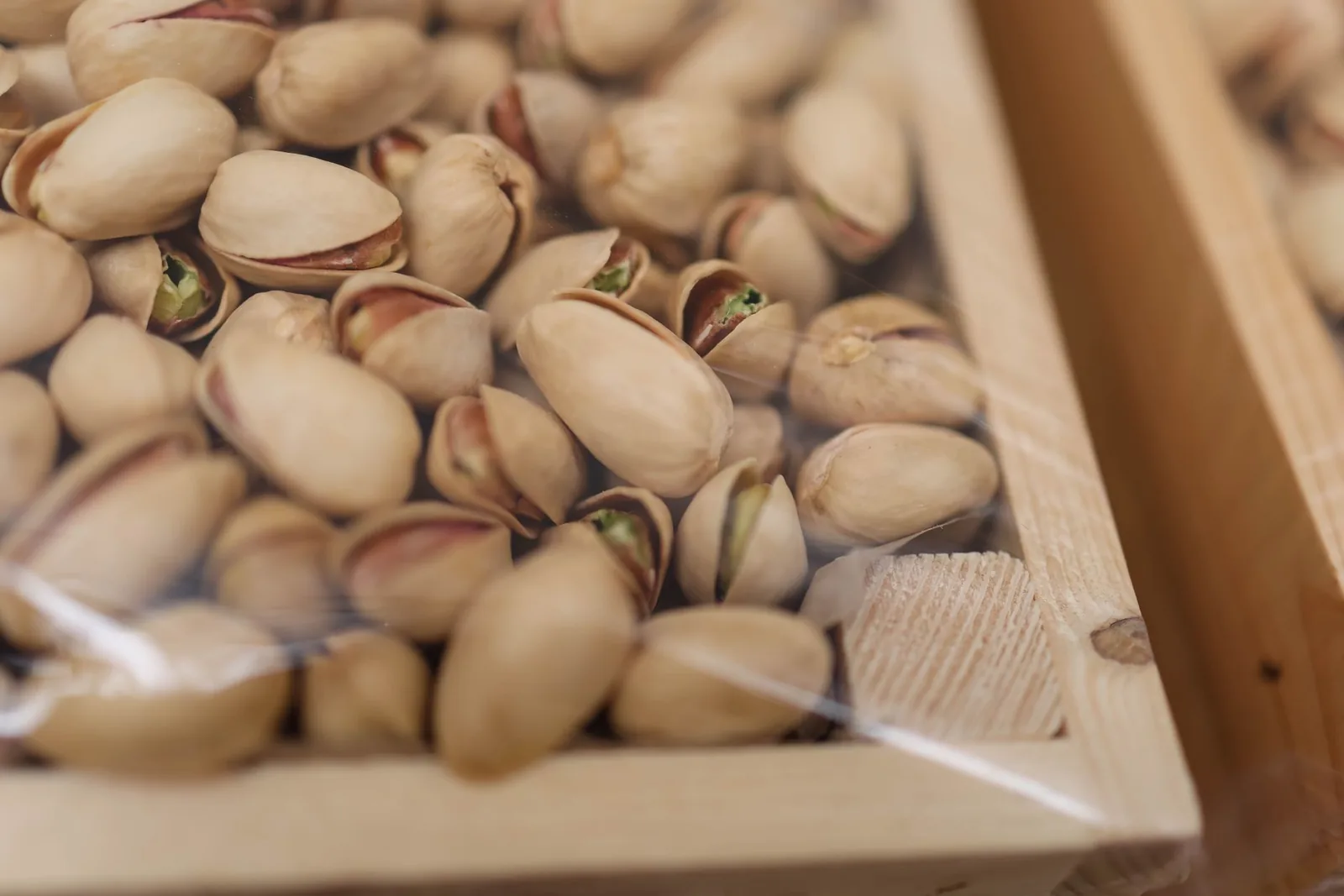 Pistaches en coque présentées dans une cagette de bois sur un étal, comme sur le quai d'Égine