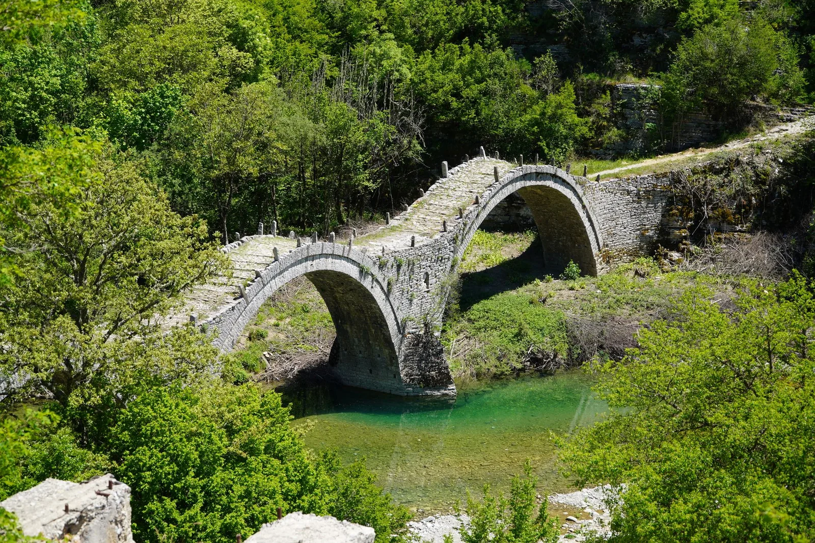 Le pont de pierre à trois arches de Plakida, ou pont Kalogeriko, au-dessus d'une rivière verte près de Kipoi dans les Zagoria