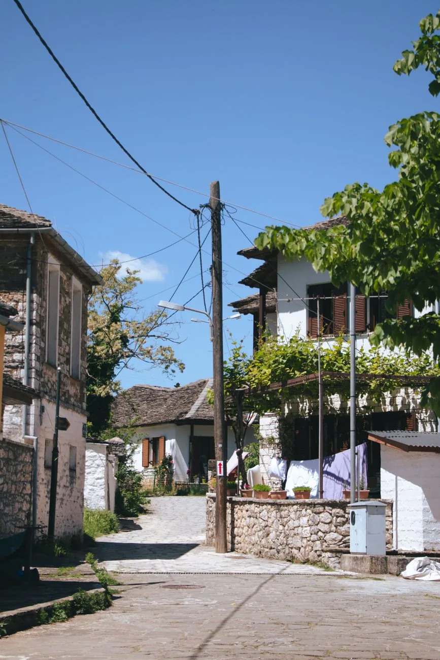Ruelle pavée bordée de maisons blanches et de pierre, avec une treille, dans un quartier ancien d'Ioannina