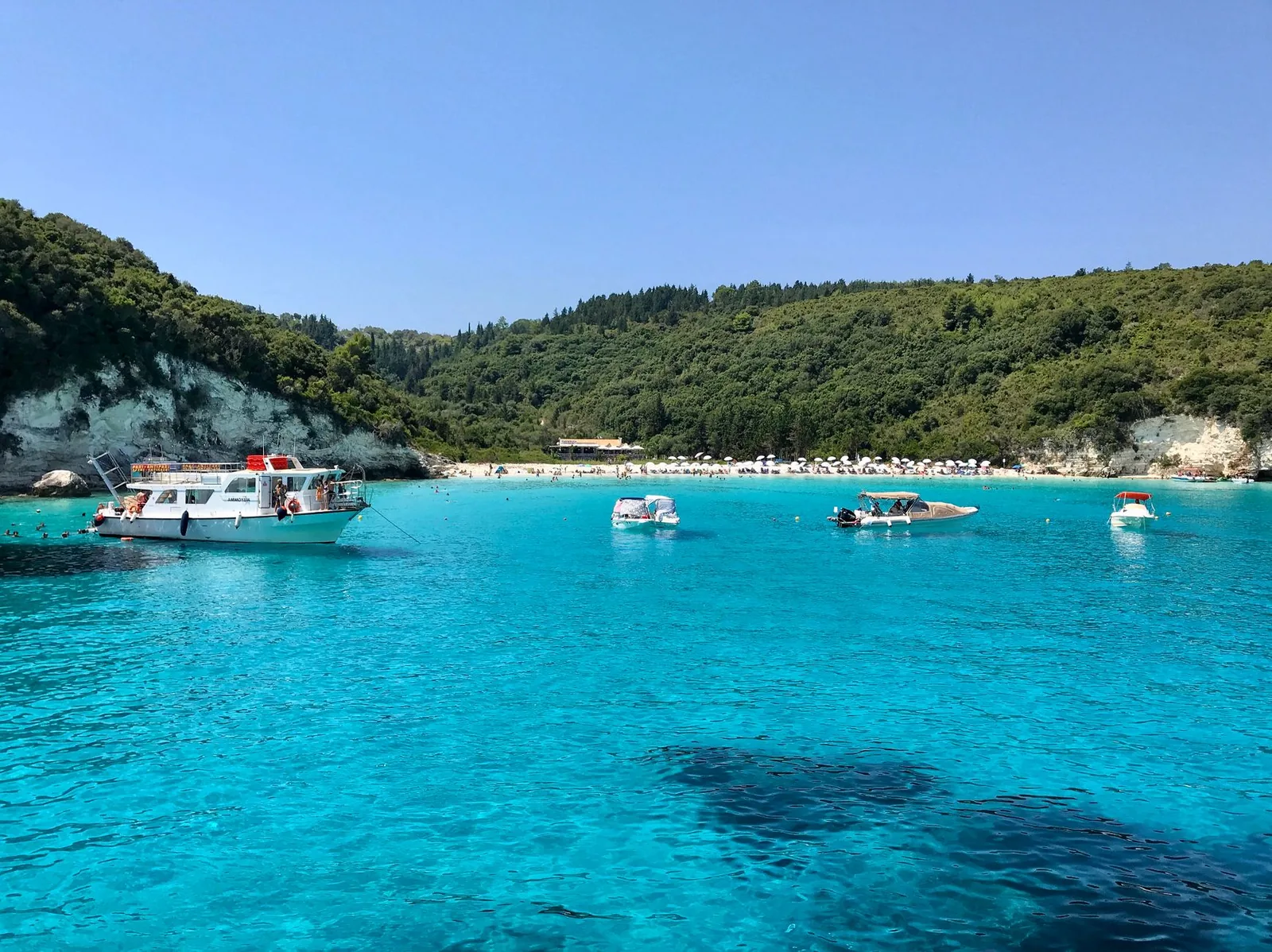 Les eaux turquoise transparentes de la plage de Voutoumi, à Antipaxos, avec des bateaux à l'ancre