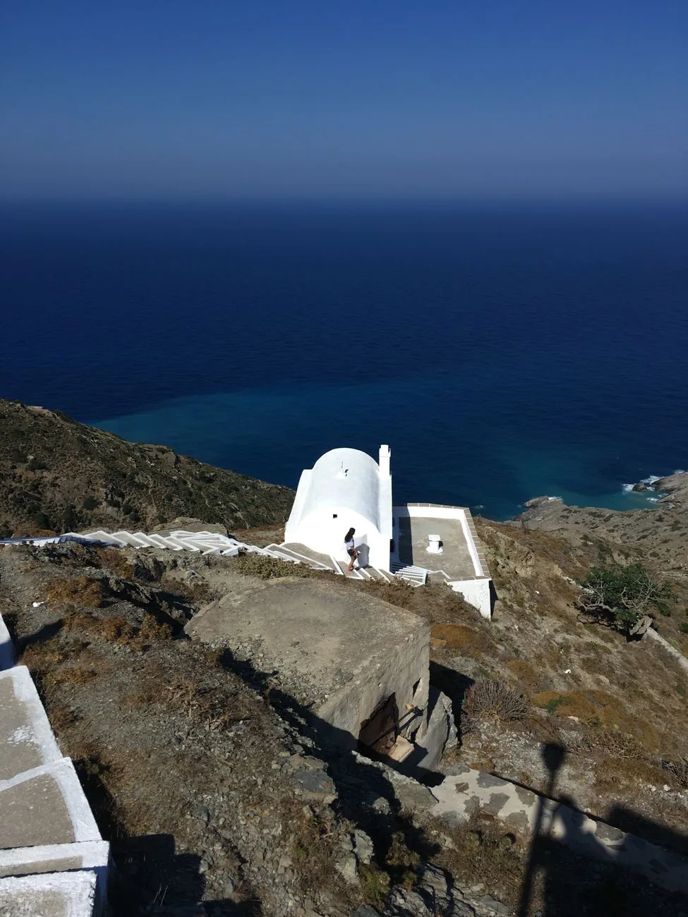 Chapelle blanche isolée au sommet d'une colline dominant la mer Égée, à Ios