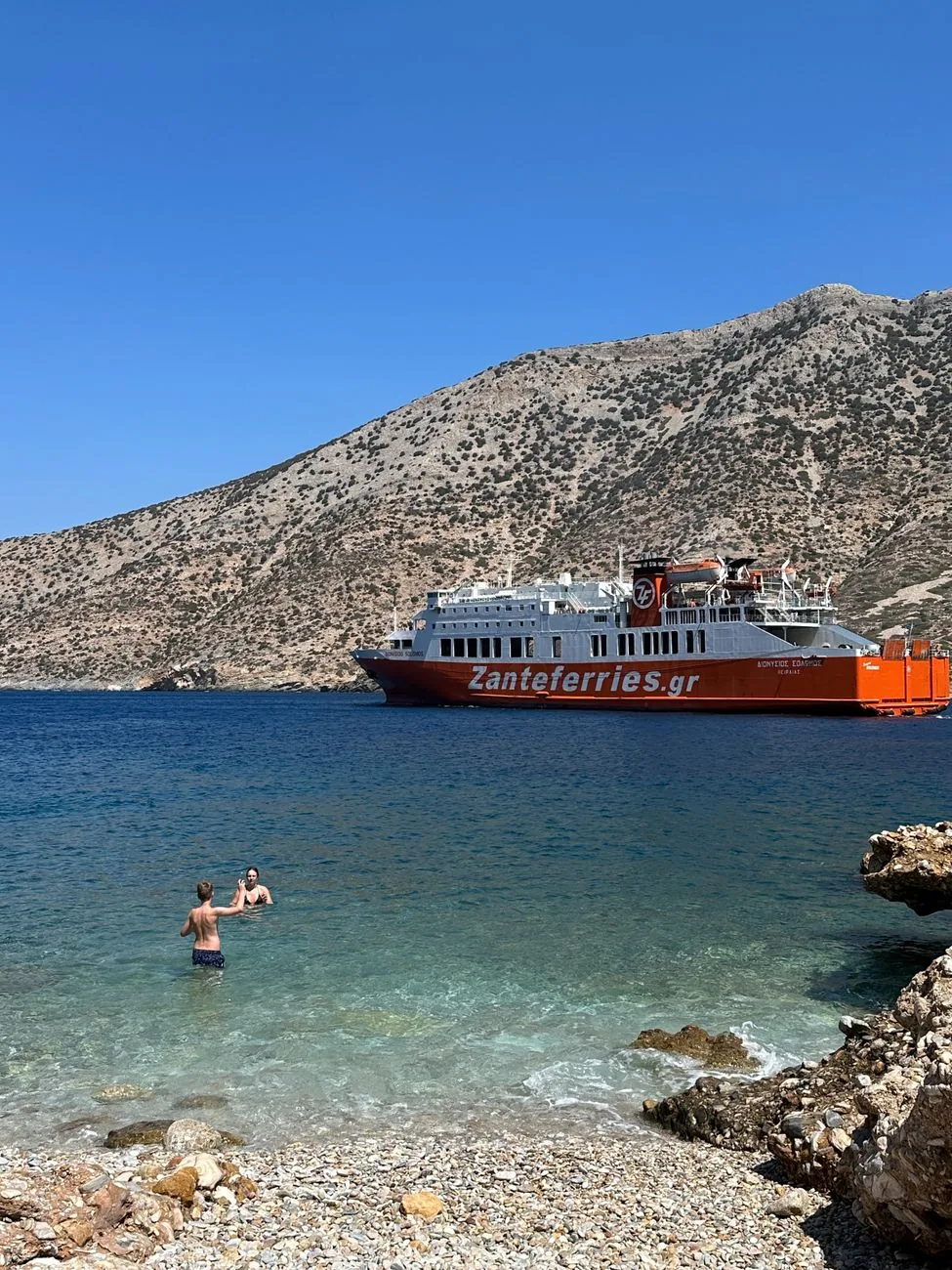 Ferry grec accosté dans une baie aux collines arides, à l'arrivée sur une île des Cyclades