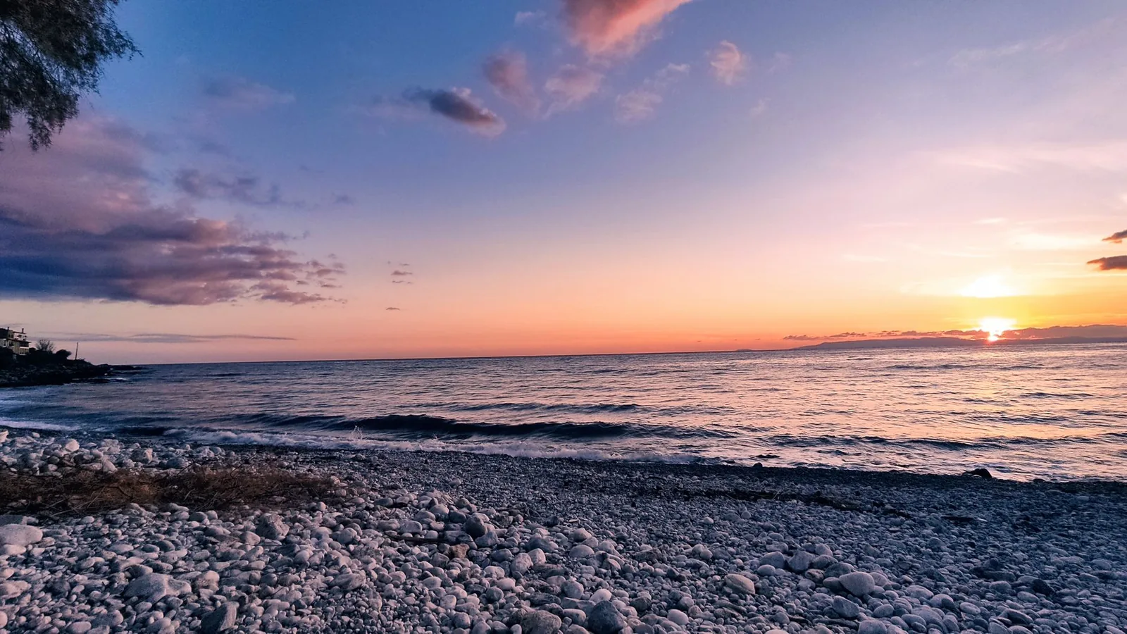 Plage de galets au coucher du soleil sur la côte du golfe de Messénie, avec les montagnes qui descendent vers la mer, semblable au front de mer de Kalamata