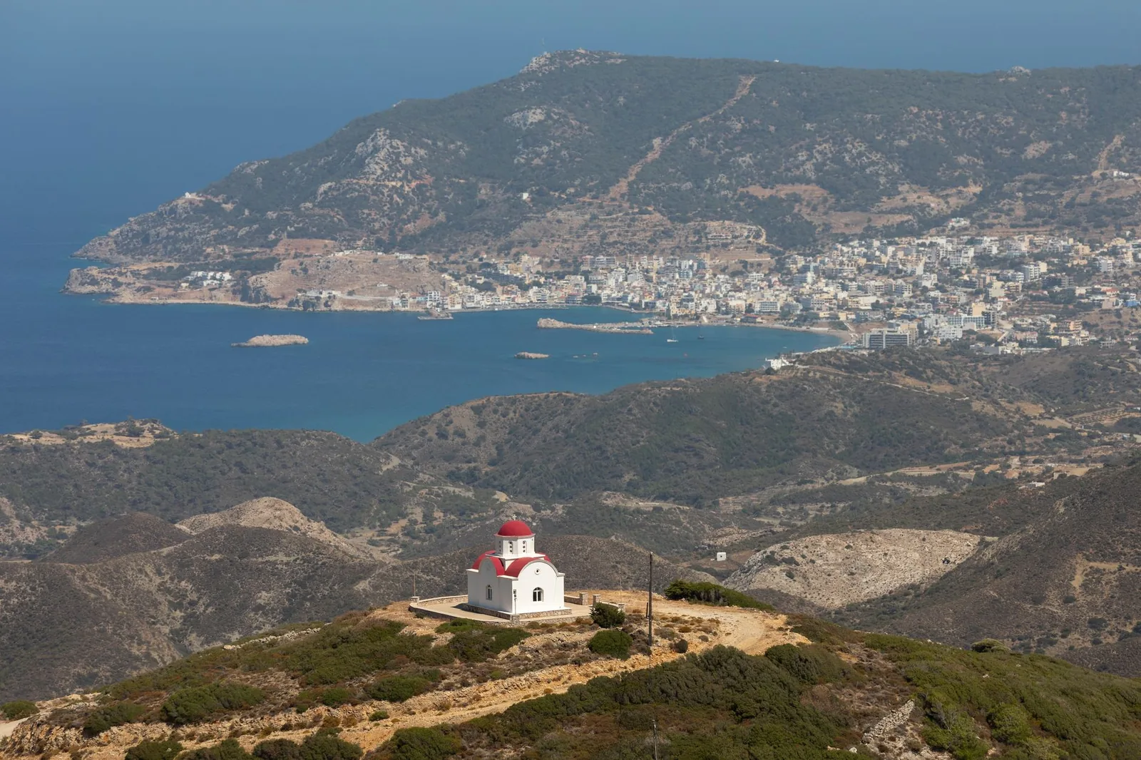 Vue en surplomb de Pigadia à Karpathos, ses immeubles blancs étagés autour de la baie où se concentrent les hébergements de l'île