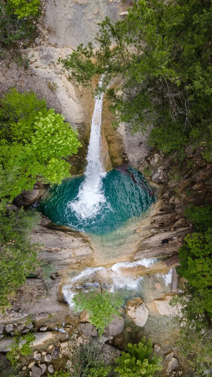 La cascade de Dimosari tombant dans son bassin d'eau claire au fond d'une gorge boisée, au-dessus de Nydri à Lefkada