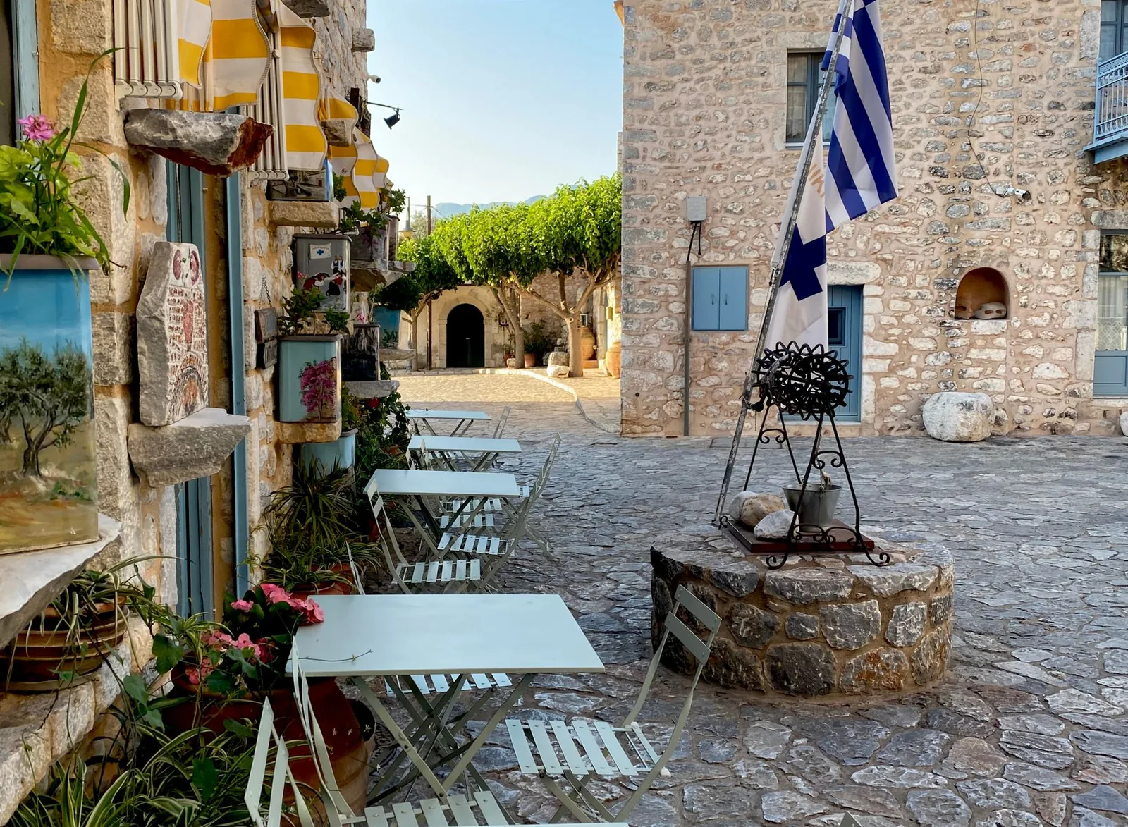 Place pavée d'Aréopoli dans le Magne, ses maisons de pierre, son puits et le drapeau grec, en fin de journée