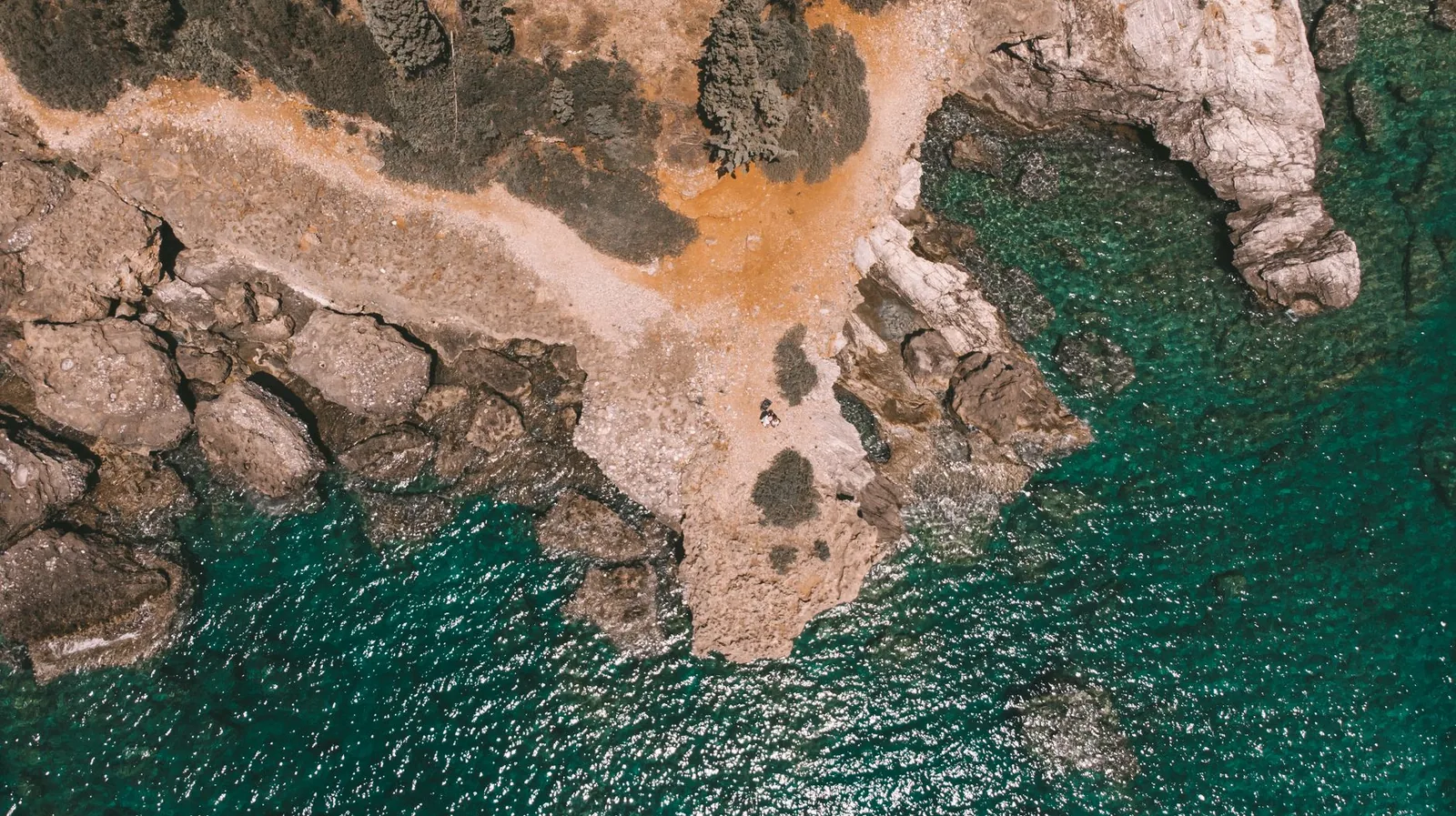Crique aux eaux turquoise et transparentes bordée de rochers clairs sur une côte grecque