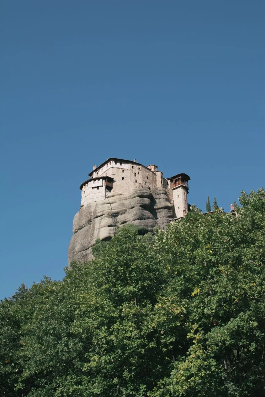 Le monastère de Roussanou perché sur son rocher rond, entouré d'arbres, aux Météores