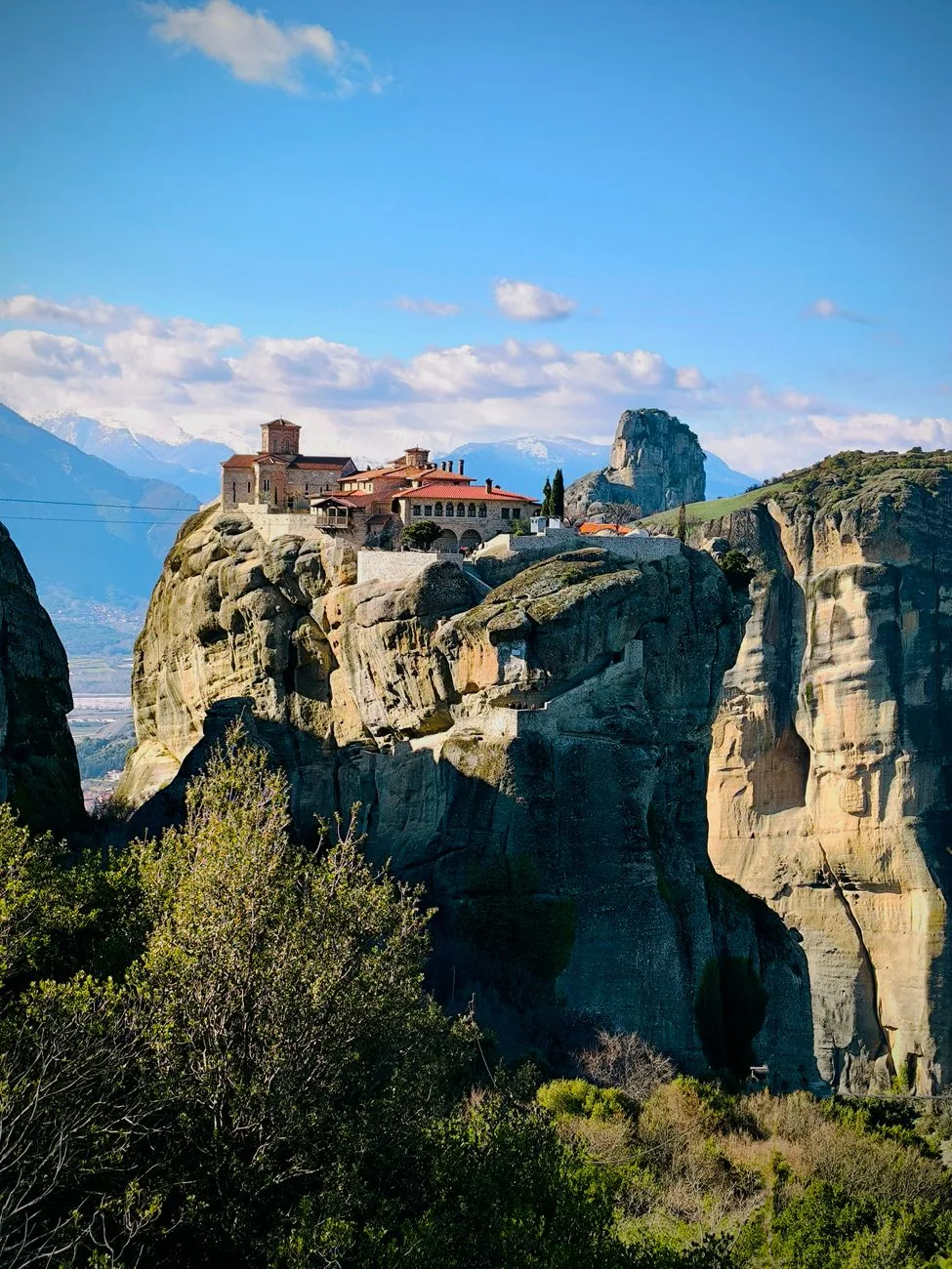 Le monastère de la Sainte-Trinité (Agia Triada) isolé sur son pilier rocheux, devant les montagnes du Pinde enneigées, aux Météores