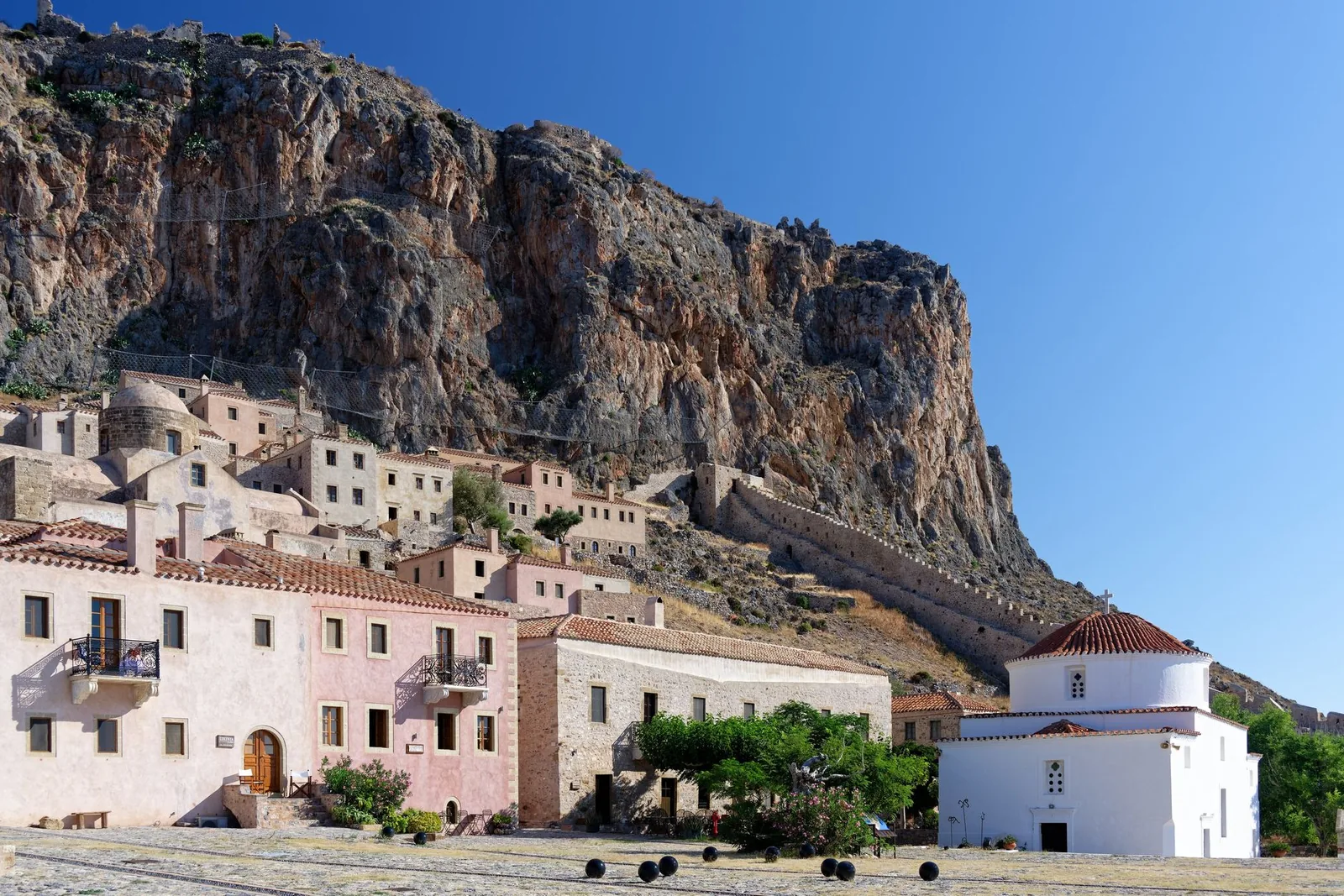 La place centrale de Monemvasia, ses boulets de canon au sol et l'ancienne mosquée ottomane devenue musée archéologique, sous la falaise