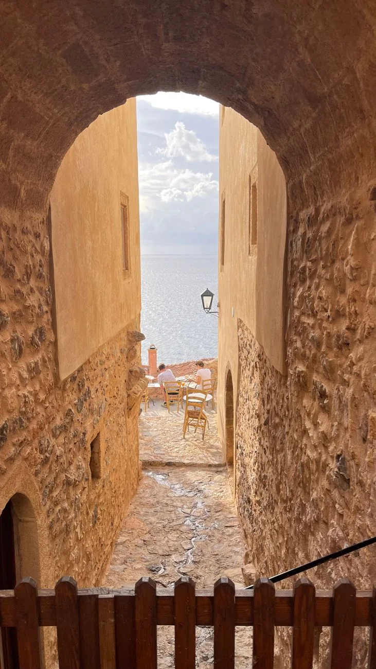 Passage voûté en pierre dans les remparts de Monemvasia, ouvrant sur une ruelle et la mer Égée