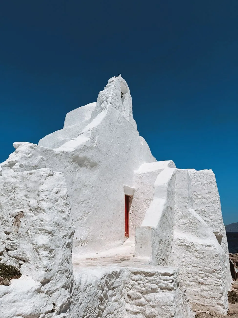 Église blanche sculpturale de Panagia Paraportiani à Mykonos sous un ciel bleu intense
