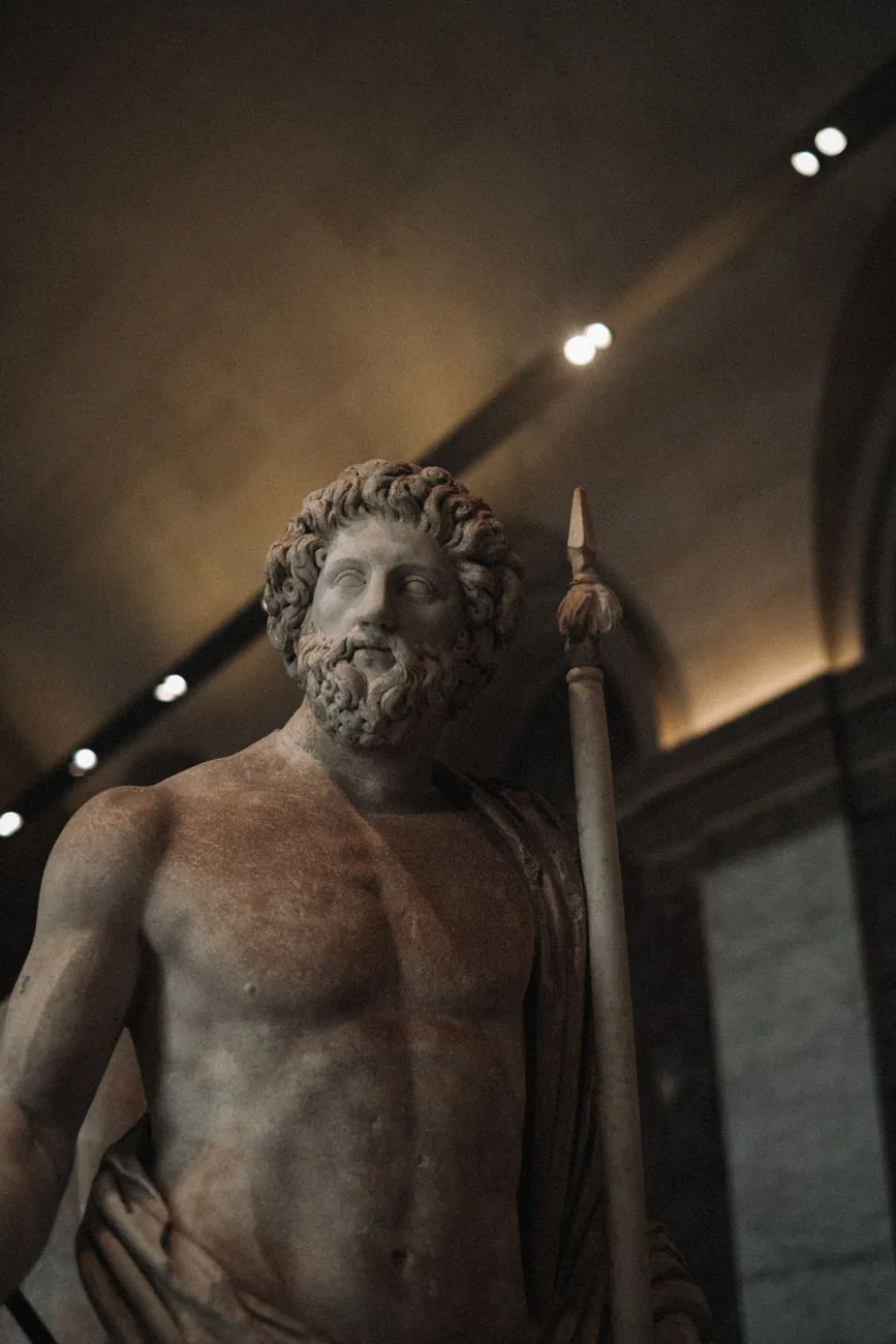 Statue antique en marbre d'un dieu grec barbu tenant un sceptre, identifiée comme Zeus, exposée en musée