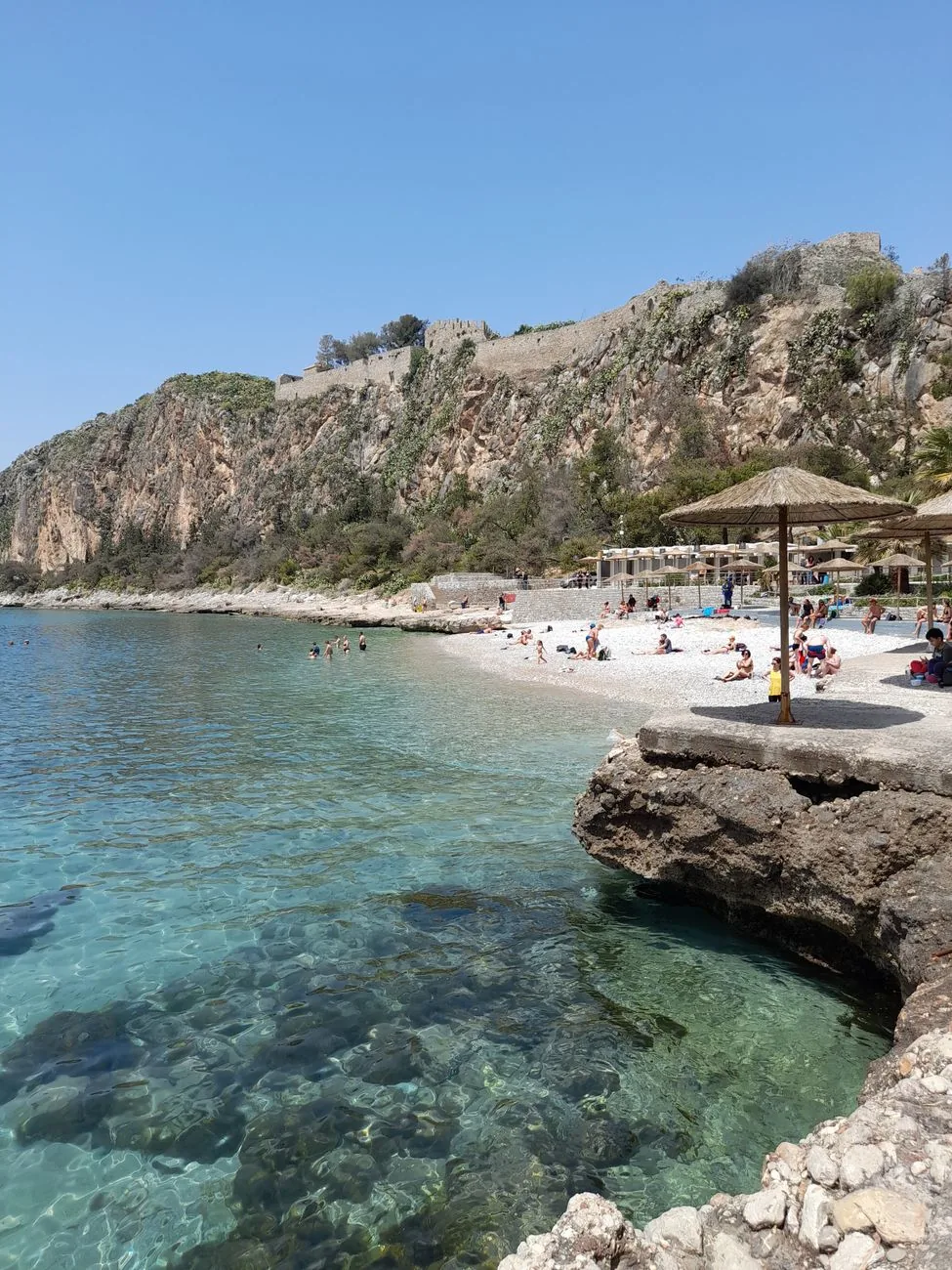 La petite plage de galets d'Arvanitia et son eau turquoise, au pied des falaises de l'Acronauplie, à Nauplie