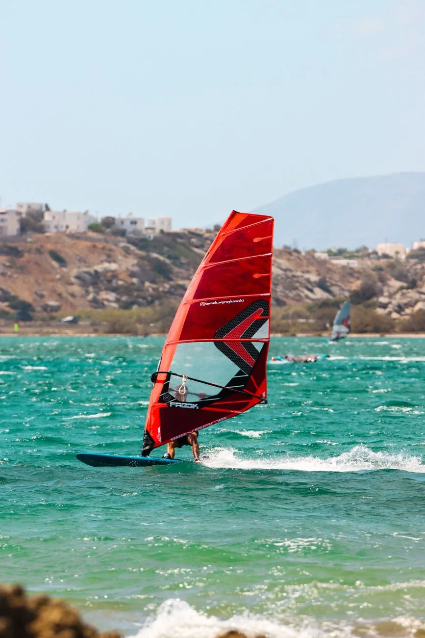 Planche à voile filant sur l'eau turquoise et venteuse de Mikri Vigla, spot de windsurf de Naxos
