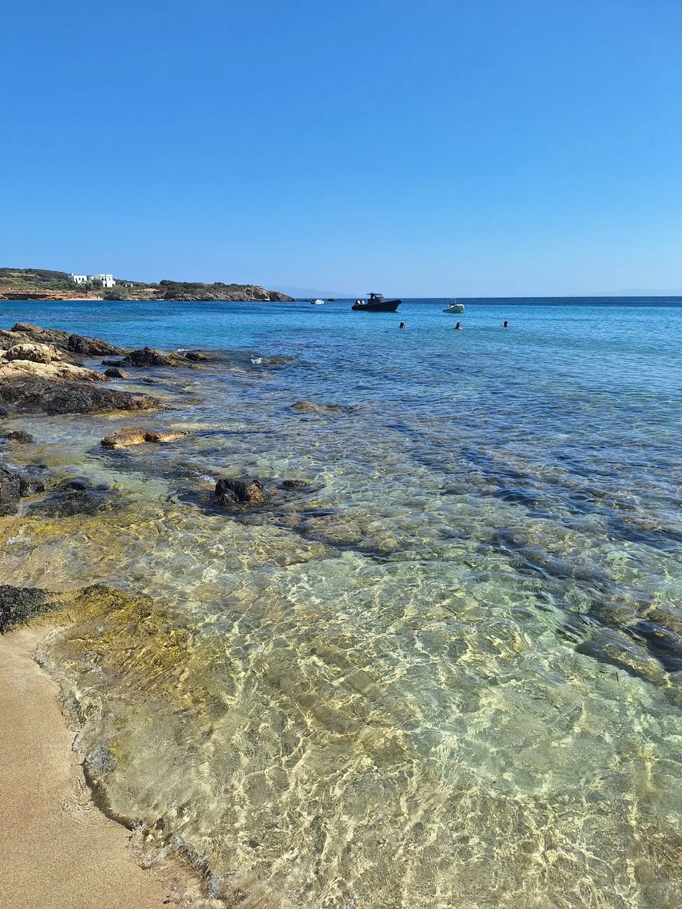 Crique aux eaux transparentes avec baigneurs et bateaux au mouillage, sur la côte est de Paros