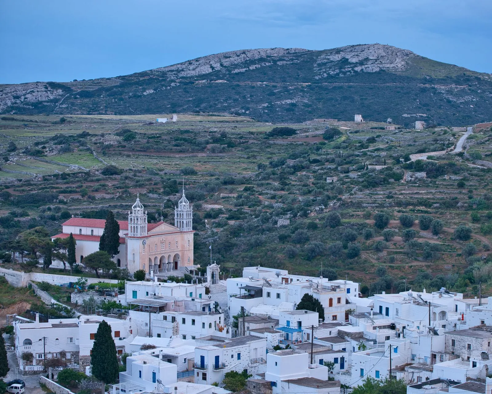 Village blanc aux clochers jumeaux de son église, au pied des montagnes dans l'arrière-pays de Paros