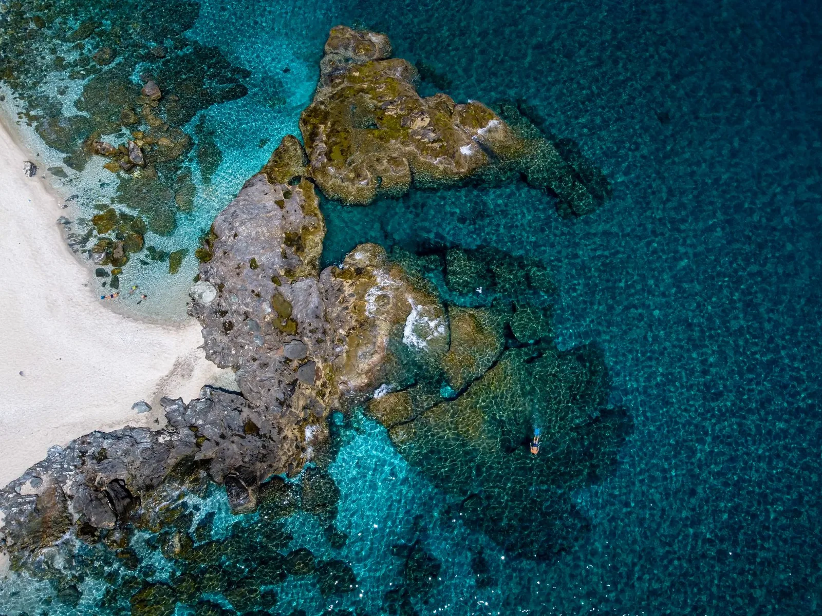 Eau turquoise et éperon de roche blanche séparant deux anses de galets sur la côte est du Pélion