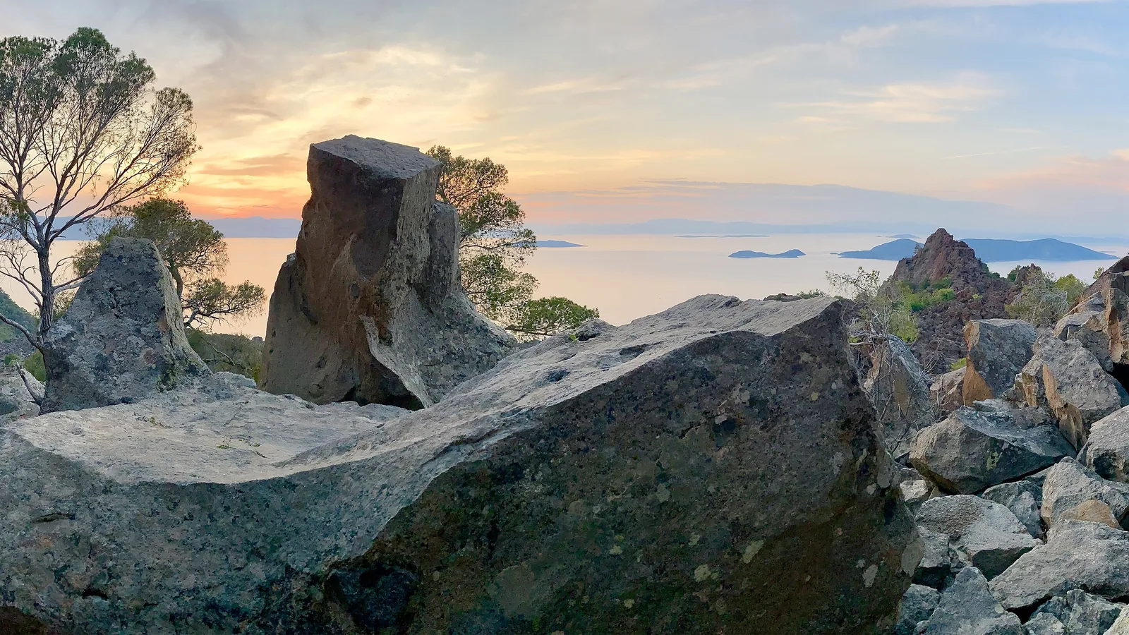 Blocs de lave du volcan de Méthana au coucher du soleil, le golfe Saronique en fond