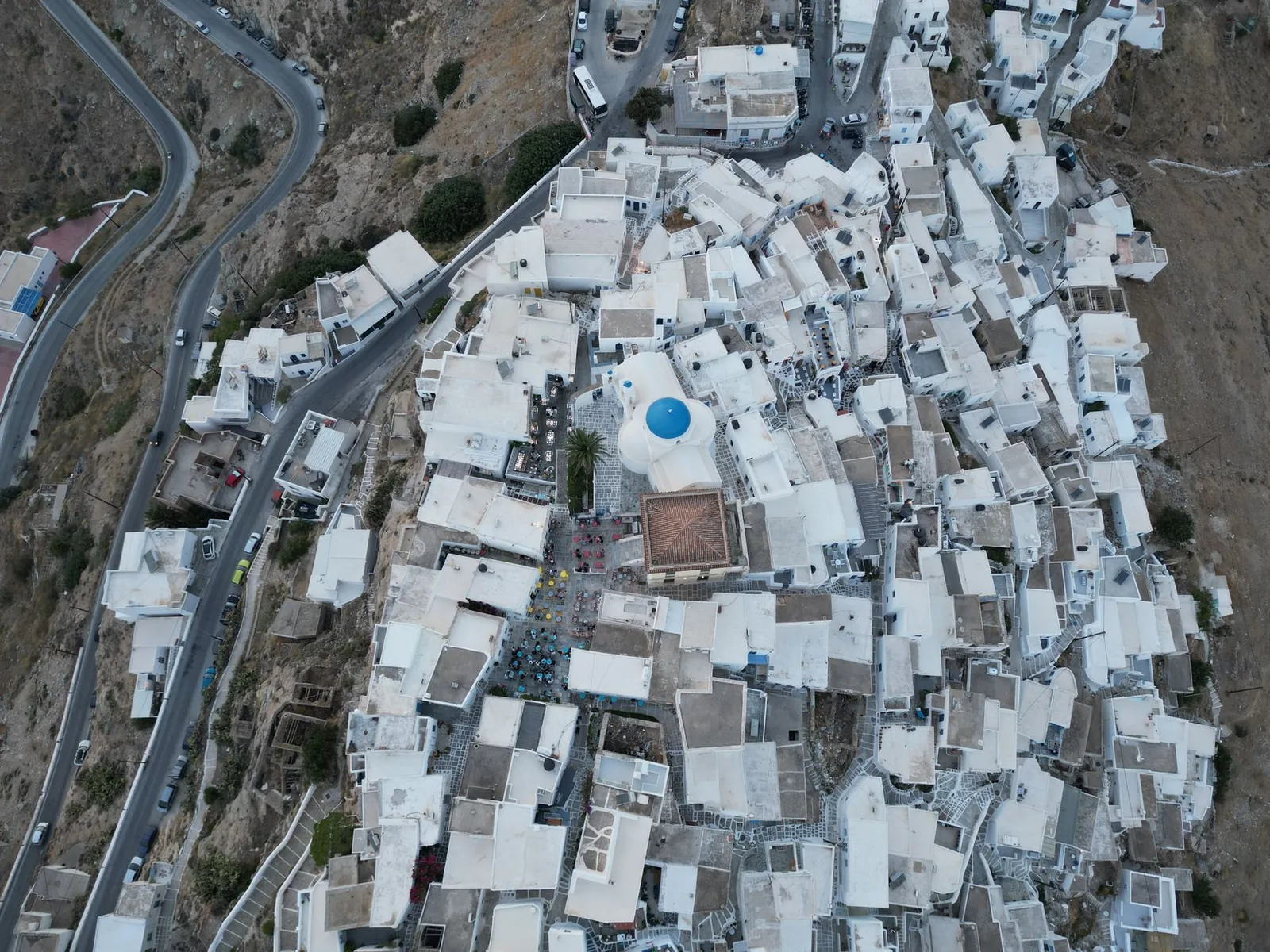 Vue aérienne de la Chora de Sérifos, maisons blanchies à la chaux serrées les unes contre les autres sur le flanc de la colline, avec la route en lacets qui monte depuis Livadi