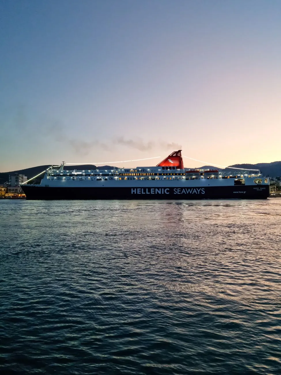 Ferry grec illuminé à quai dans un port des Cyclades au crépuscule, à l'arrivée à Sifnos
