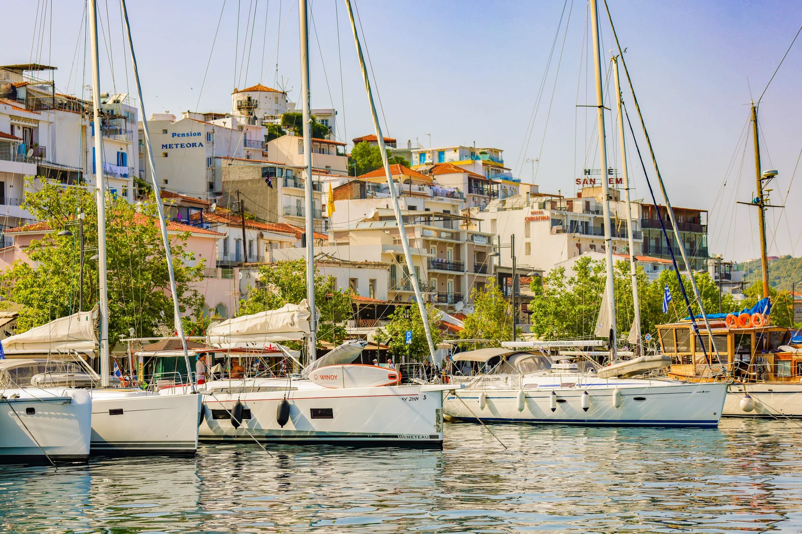 Voiliers amarrés le long du quai du port de Skiathos, devant les maisons et les terrasses de la ville