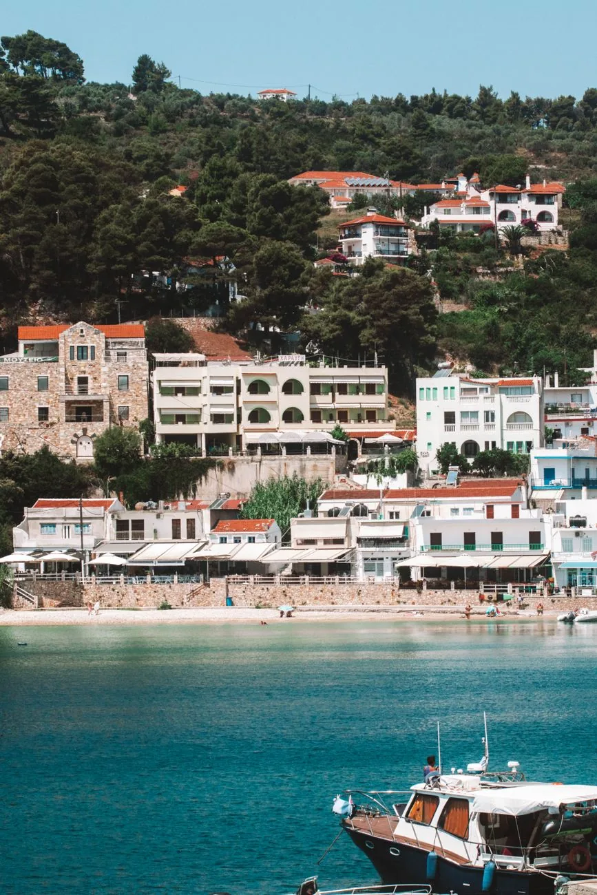 Le port de Patitiri à Alonissos, ses hôtels blancs étagés dans les pins au dessus de la plage et un bateau amarré